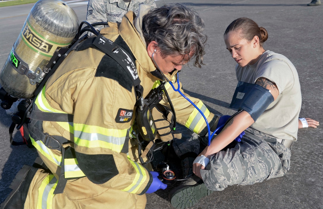 Mr. William R. Stamey Jr., Fire Emergency Services crew chief assigned to the 6th Civil Engineer Squadron, administers medical aid to Senior Airman Sarah Eby, fuels system Repairman apprentice with the 6th Maintenance Squadron, during an Emergency Management exercise at MacDill Air Force Base, Fla., Sept. 13, 2016. Eby was first taken through decontamination before being released for medical treatment. (U.S. Air Force photo by Senior Airman Vernon L. Fowler Jr.)