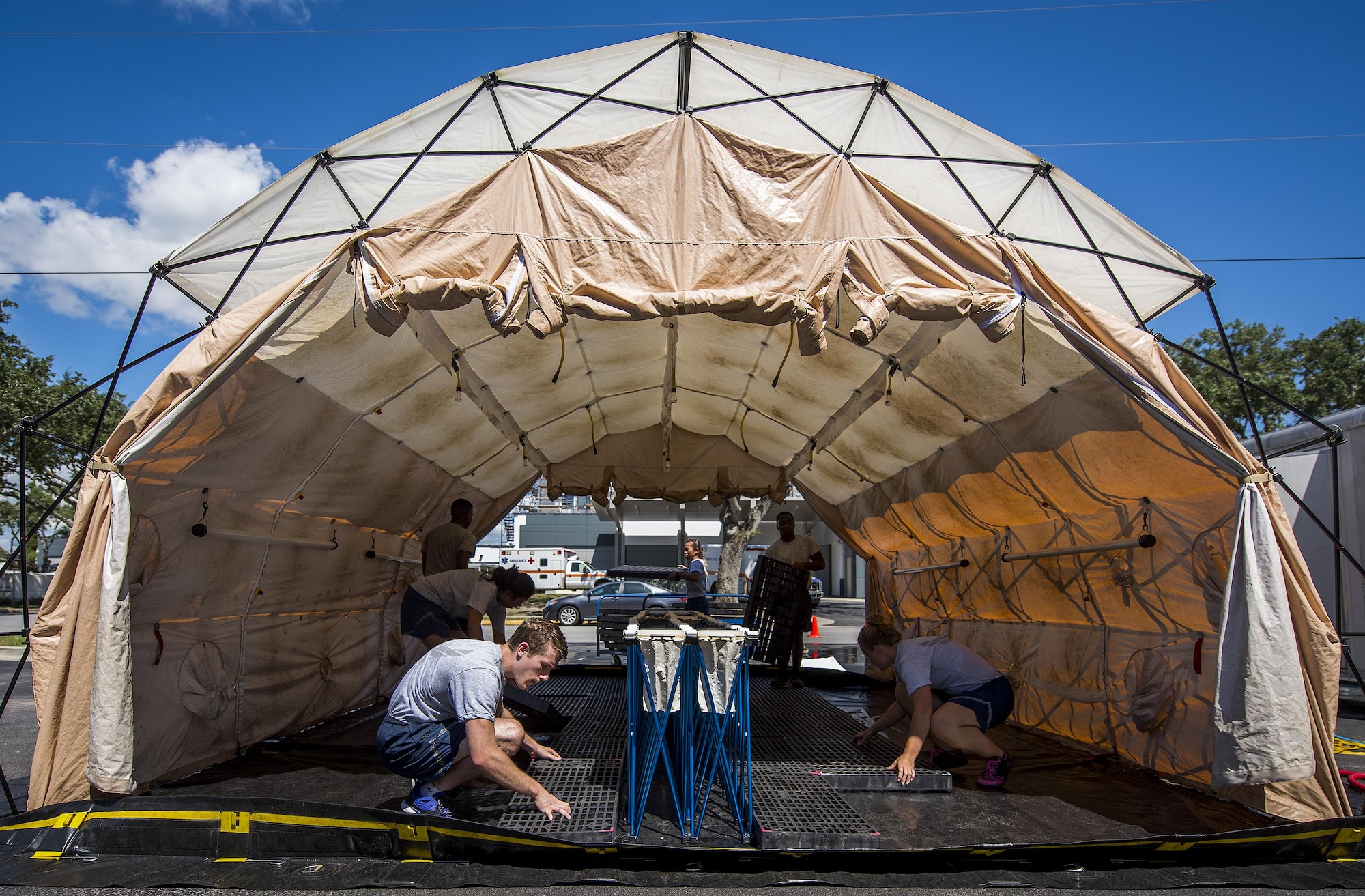 Airmen from the 96th Medical Group, set up floor grates inside a tent during a decontamination procedures exercise at the Hospital Sept. 15 at Eglin Air Force Base, Fla.  The Airmen worked quickly to erect and set up a decontamination tent with running water and drainage and donned their protective gear.  Despite the heat, the team was fully set up and ready to receive patients in under 12 minutes. (U.S. Air Force photo/Samuel King Jr.)