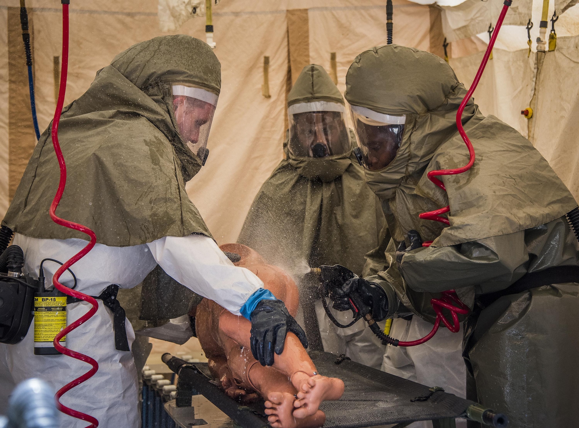 Airmen spray down a simulated victim during the decontamination procedures exercise at the Hospital Sept. 15 at Eglin Air Force Base, Fla.  The 96th Medical Group Airmen worked quickly to erect and set up a decontamination tent with running water and drainage and donned their protective gear.  Despite the heat, the team was fully set up and ready to receive patients in under 12 minutes. (U.S. Air Force photo/Samuel King Jr.)