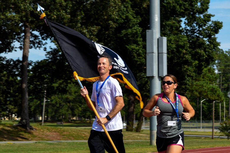 Retired Lt. Col. John Coulter (left) runs with the Prisoners of War/Missing in Action flag alongside Senior Master Sgt. Rebecca Alaniz, 4th Medical Operations Squadron superintendent, Sept. 14, 2016, at Seymour Johnson Air Force Base, North Carolina. Coulter and Alaniz kicked off the 24-hour run that ended just before the closing ceremony the following day. (U.S. Air Force photo by Airman Shawna L. Keyes)