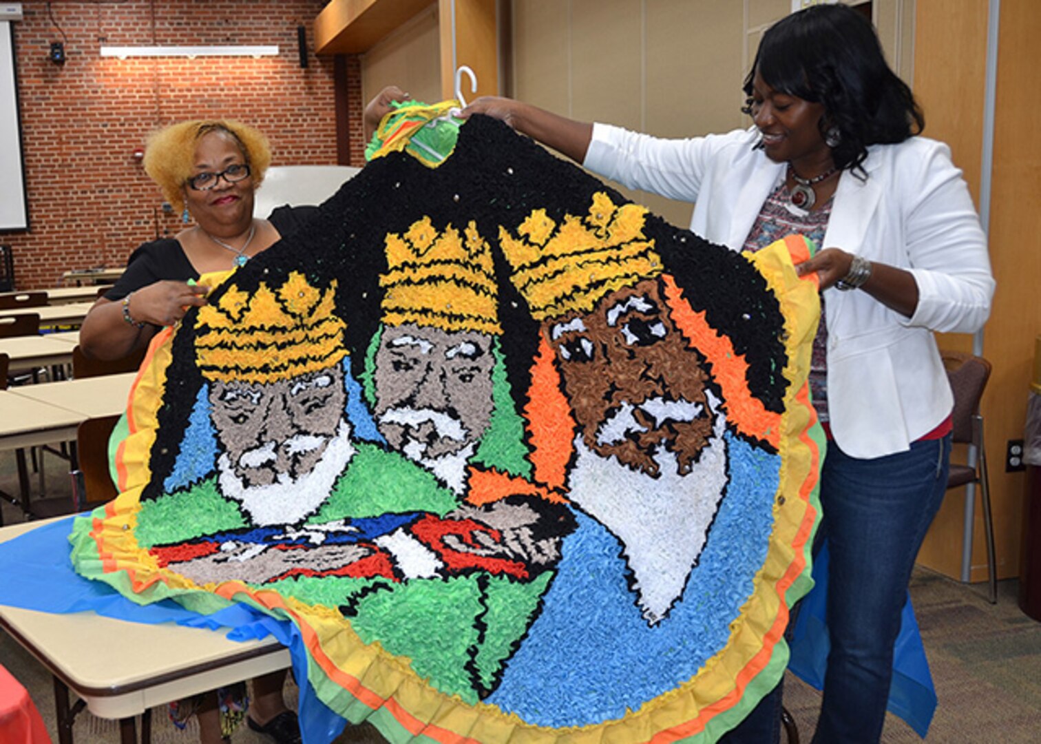 DLA Aviation Equal Employment Opportunity and Diversity Office employees, Carolyn Clark-Swann, EEOD assistant, and Victoria Seabury, complaints manager, admire the cape from a costume worn in the Festival De Mascaras de Hatillo [Hatillo Masks Festival] held each year on Dec. 28, on the North coast of Puerto Rico. This item was part of exhibits displayed during a Hispanic Heritage Month kickoff ceremony held Sept. 16, 2016 in the Lotts Conference Center on Defense Supply Center Richmond, Virginia.