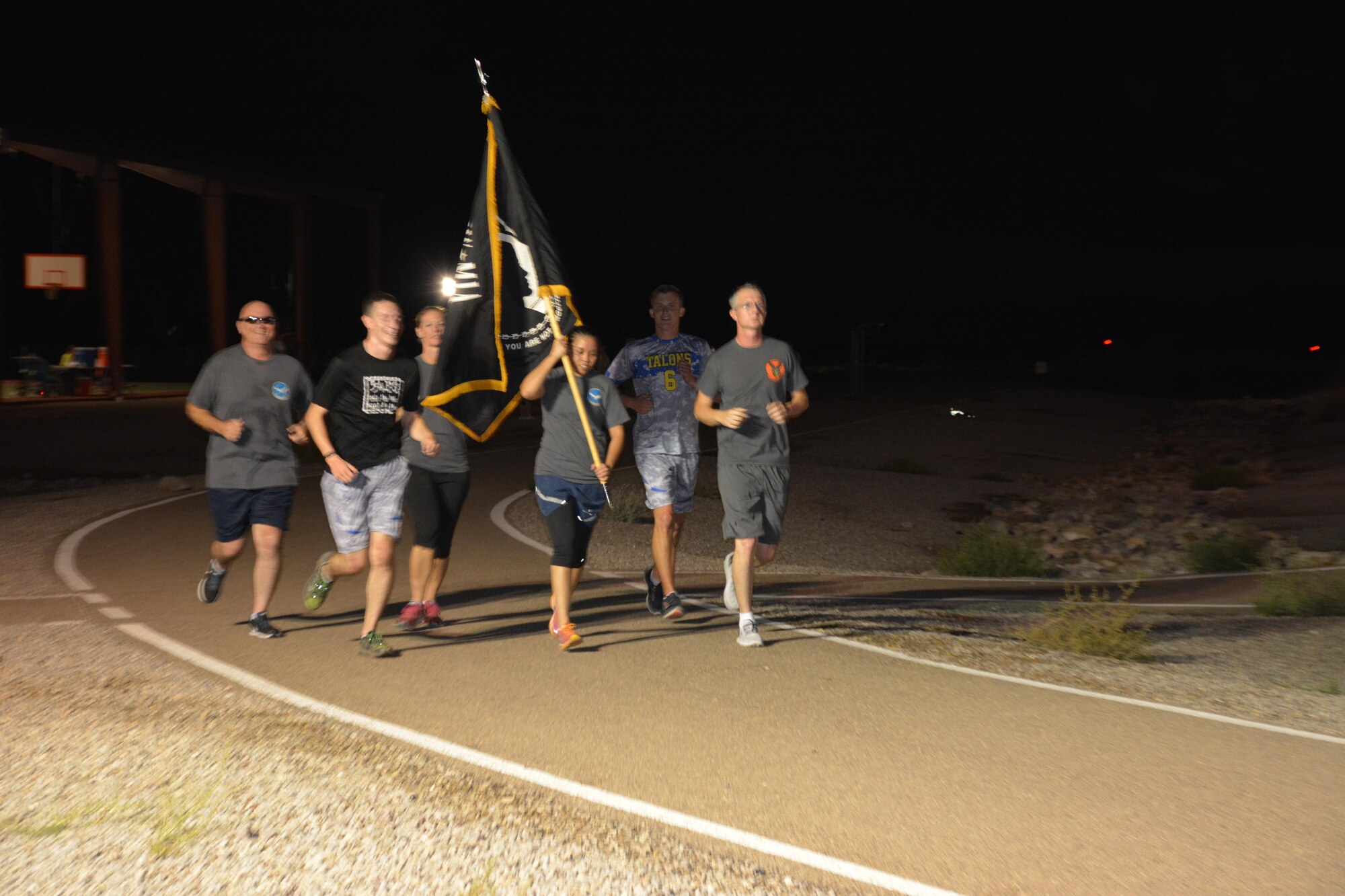 Members of Team Holloman run with the POW/MIA flag during the annual POW/MIA remembrance run at Holloman AFB, N.M., on Sept. 15, 2016. The run, which lasted 24 hours and involved units from all over Holloman, was in remembrance of prisoners of war and those still missing in action. (U.S. Air Force photo by SSgt Warren Spearman)