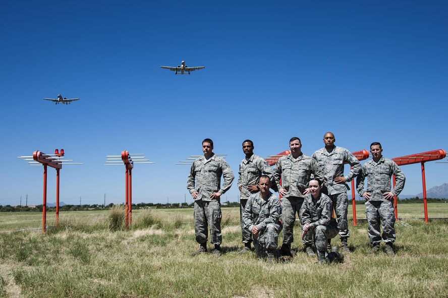 U.S. Airmen from the 355th Operations Support Squadron pose for a photograph in front of Runway 12's newly activated Instrument Landing System as two A-10C Thunderbolt II aircraft fly above Davis-Monthan Air Force Base, Ariz., Sept. 15, 2016. The ILS provides approaching aircraft with horizontal and vertical guidance relative to the centerline and the threshold of the runway for an accurate landing approach. (U.S. Air Force photo by Senior Airman Chris Drzazgowski)