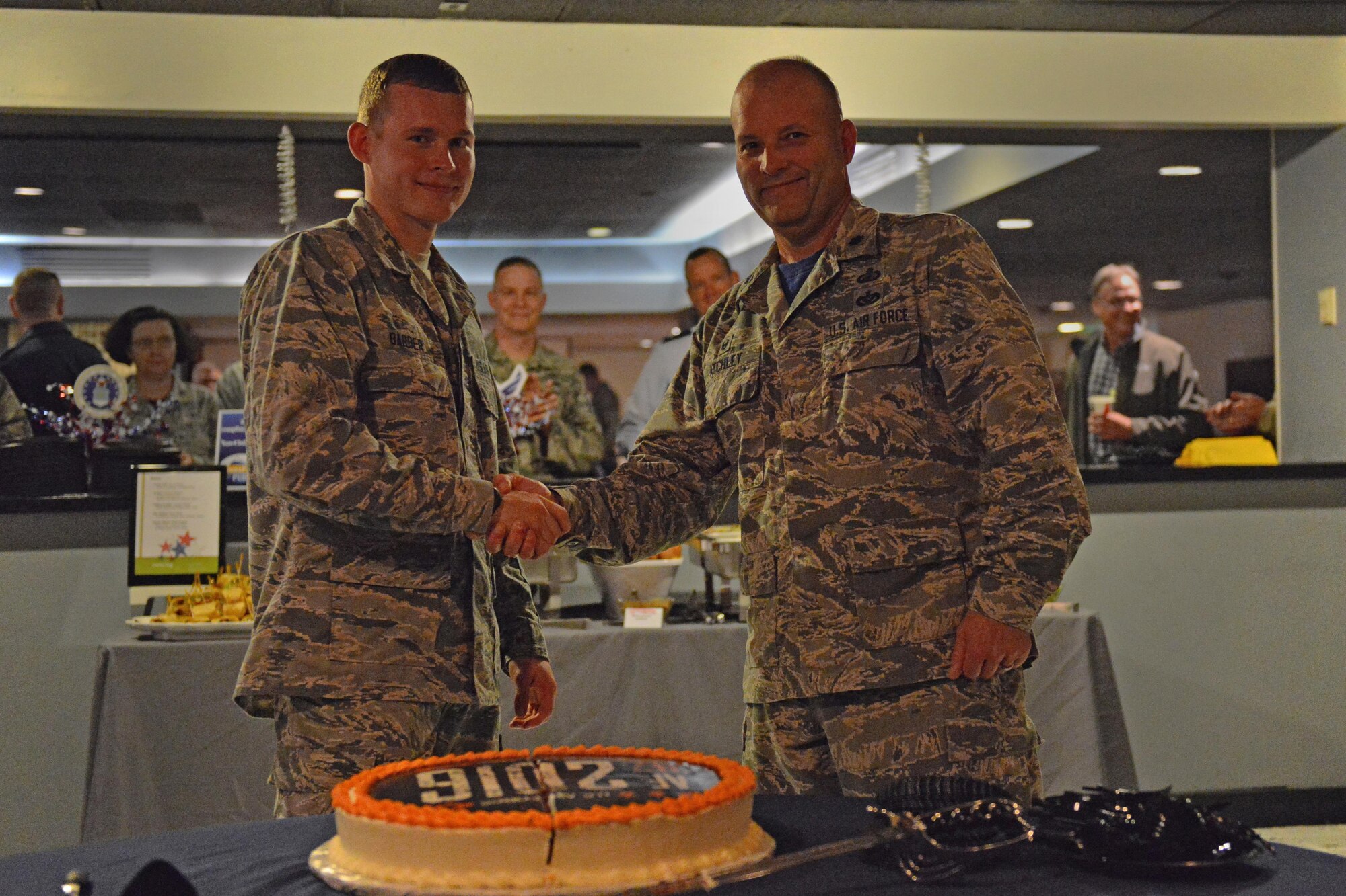 Airman Basic Zachary Barber, 773d Logistics Readiness Squadron, parachute rigger, and Air Force Lt. Col. James Atchley, 673d Contracting Squadron, commander shake hands after cutting the cake at Permafrost Pub, Joint Base Elmendorf-Richardson, Sept 16 in celebration of the Air Force's 69th birthday. It is customary for the Airmen with the least time in service and the Airman with the most time in service present to cut the cake.