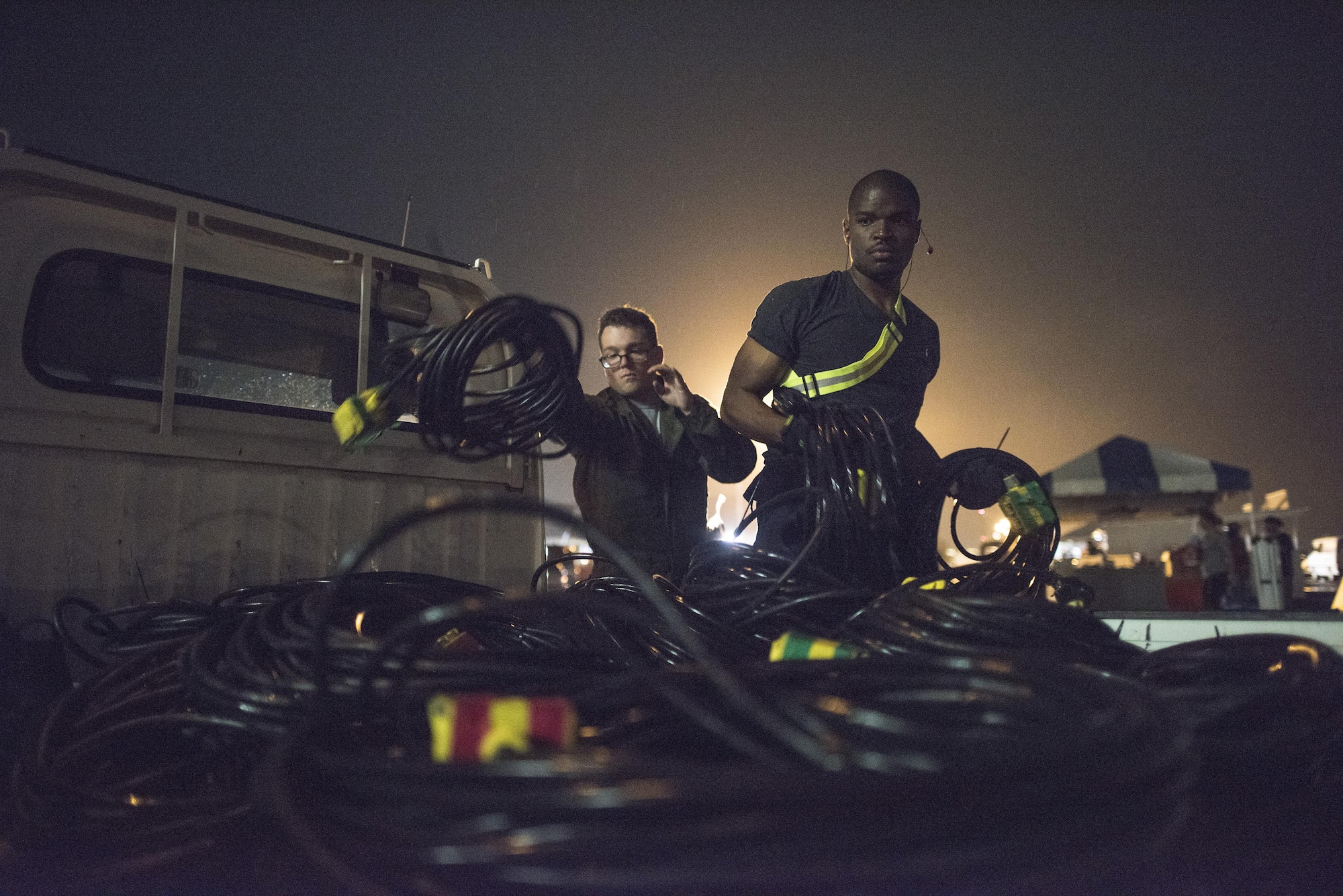 Airmen with the 374th Civil Engineer Squadron electrician shop place power cords into the back of a vehicle after the 2016 Japanese-American Friendship Festival at Yokota Air Base, Japan, Sept. 18, 2016. Thousands of feet of electrical cords were used to power vendor stands during the festival; the 374 CES engineer shop installs the cords before the festival and removes them the closing night. (U.S. Air Force photo by Staff Sgt. Cody H. Ramirez/Released)