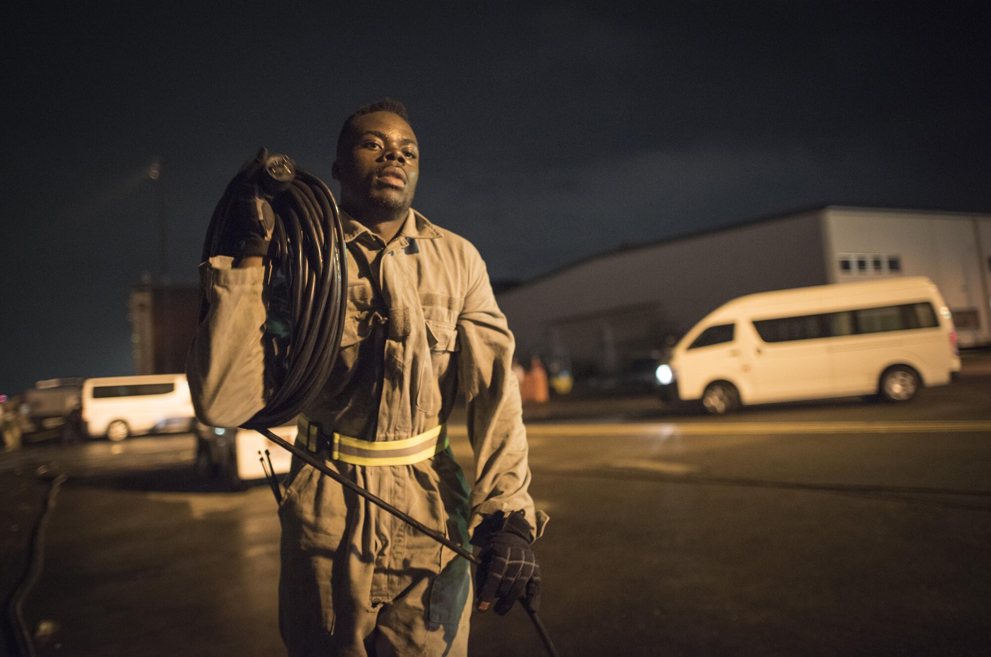 Airman 1st Class Felix Nunez, 374th Civil Engineer Squadron electrician, coils a power cord around his arm after the 2016 Japanese-American Friendship Festival at Yokota Air Base, Japan, Sept. 18, 2016. After the festival, Twelve Airmen with the 374 CES electrician shop rolled thousands of feet of power cords lining the festival grounds, assisting to return the flightline to fully operational status by early morning. (U.S. Air Force photo by Staff Sgt. Cody H. Ramirez/Released)