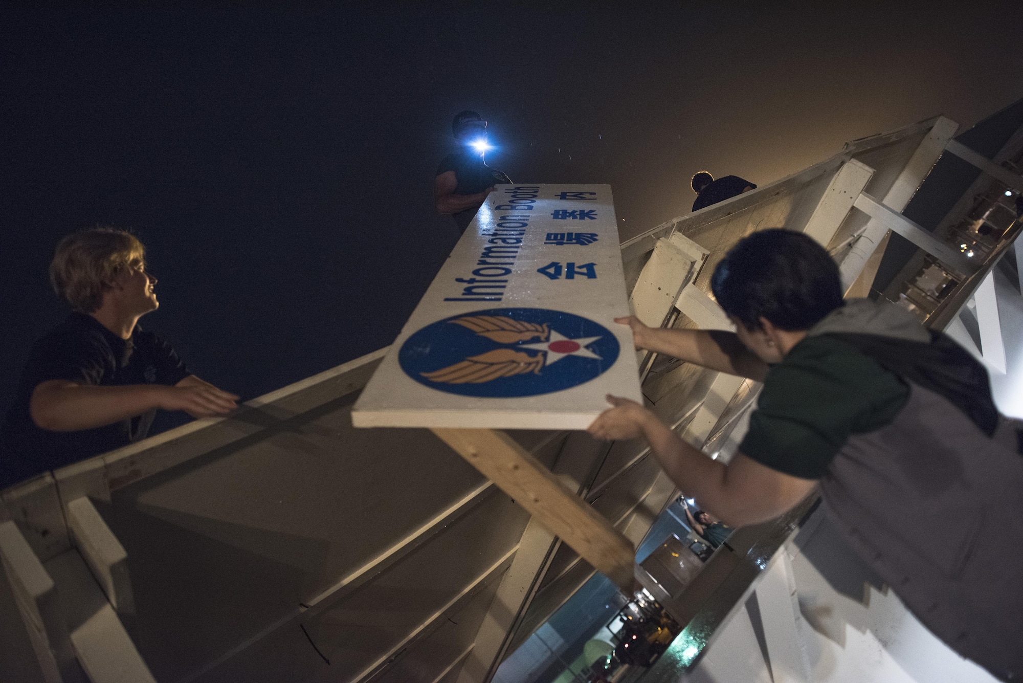 Airmen with the 374th Civil Engineer Squadron take down a sign from a booth after the 2016 Japanese- American Friendship Festival at Yokota Air Base, Japan, Sept. 18, 2016. The festival grounds take place on part of Yokota’s flightline, requiring many Airmen, contracted employees, and vendors to break down and pack their booths within a short amount of time after the festival concludes. (U.S. Air Force photo by Staff Sgt. Cody H. Ramirez/Released)