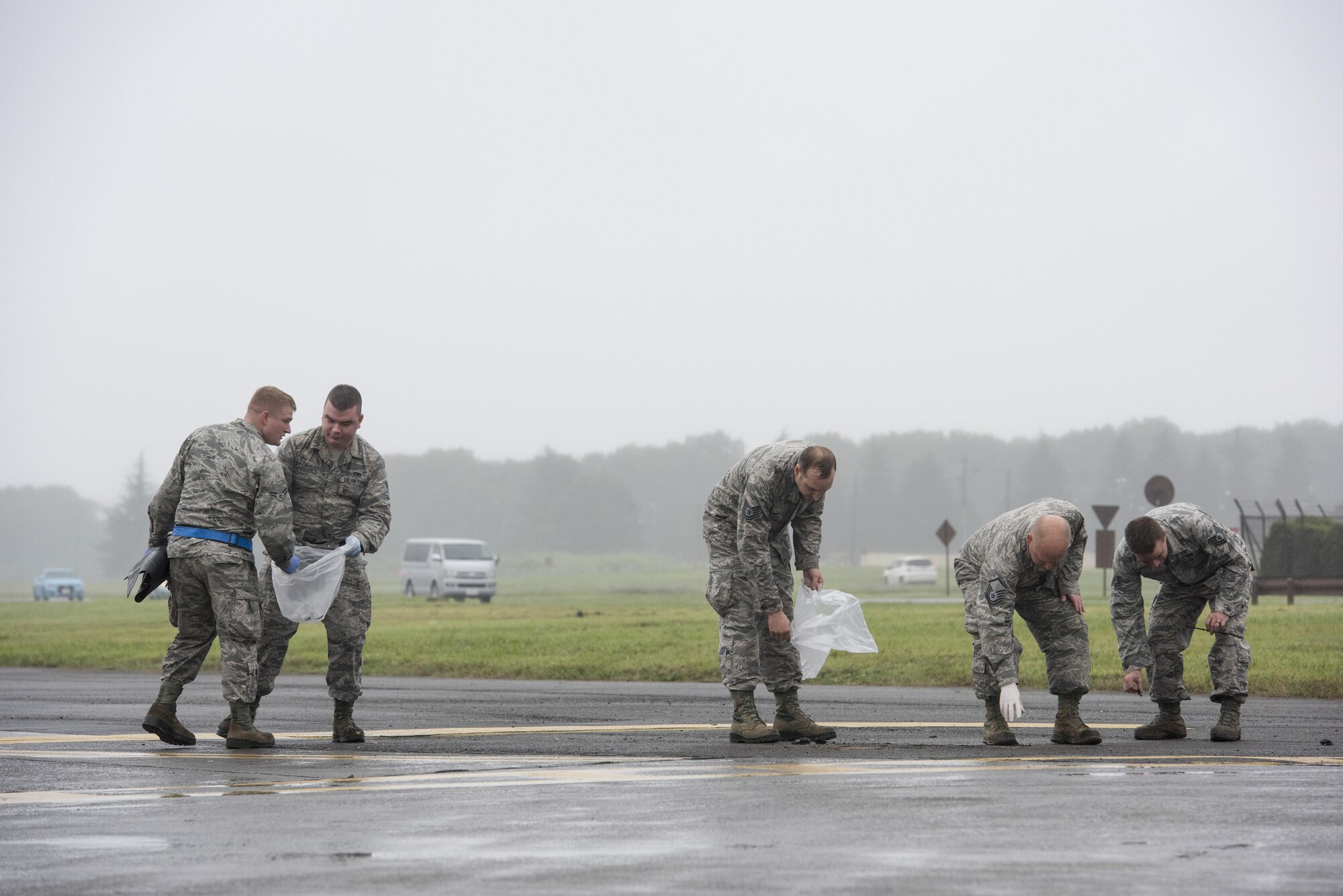 Airmen pick up debris on the flightline at Yokota Air Base, Japan, Sept. 19, 2016. Airmen spread throughout areas of the base to pick up foreign debris left over by the 2016 Japanese-American Friendship Festival, which attracted more than 135,000 people to the base. (U.S. Air Force photo by Staff Sgt. Cody H. Ramirez/Released)
