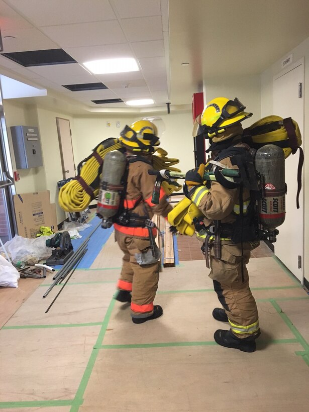 Firefighters with the Marine Corps Installation Pacific Fire and Emergency Services enter a nine story tower on Camp Courtney, Japan with hose packs to distinguish a simulated fire during emergency response training. The tower is one of 14 currently being renovated by the U.S. Army Corps of Engineers, Japan District.