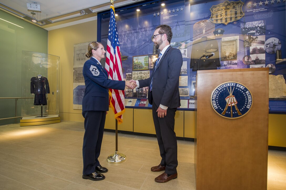Chief Master Sgt. Beth Topa, 11th Wing command chief, receives the Armed Forces Retirement Home coin from a staff member during the 69th Air Force Birthday Celebration at the AFRH in Washington, D.C., Sep. 16, 2016. Topa was the guest speaker of the event, focusing on the current state of the military and thanking the retirees for setting them up for success.