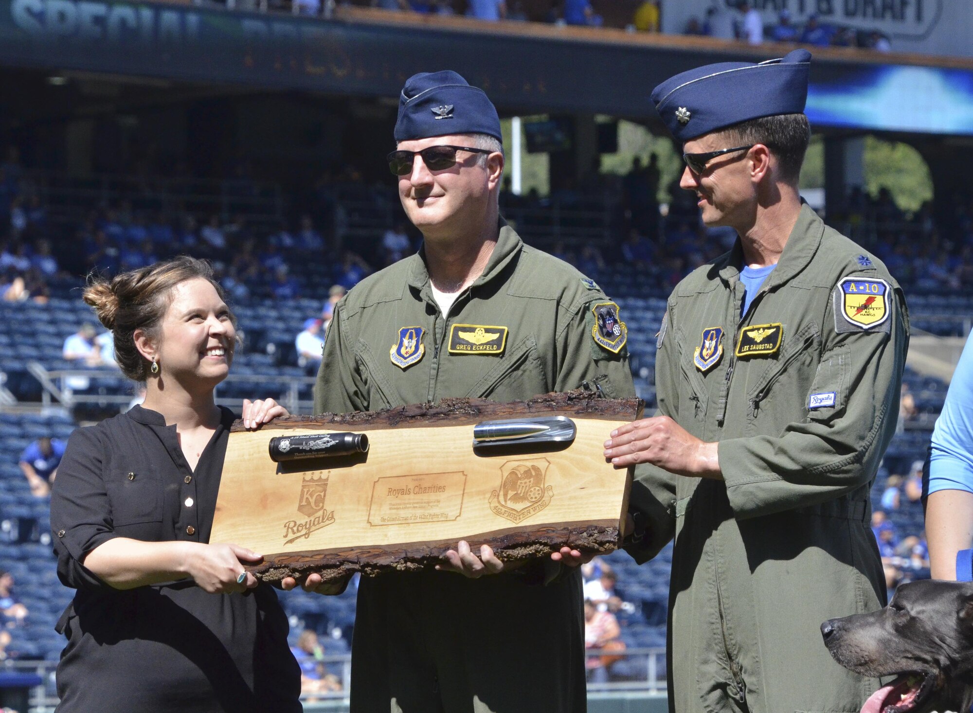U.S. Air Force Col. Gregory Eckfeld, left, 442nd Fighter Wing vice commander, and Lt. Col. Lee Saugstad, 303rd Fighter Squadron pilot, present Marie Dispenza, Director of Royals Charities, with a plaque featuring an engraved bullet casing and a bullet from an A-10 Thunderbolt II GAU-8/A 30mm cannon in appreciation of Royals Charities’ support for the 442nd Fighter Wing Airmen programs. The charity provided the Wing $11,500 that is used to support programs like the Human Resources Development Council. (U.S. Air Force photo/Senior Airman Missy Sterling)