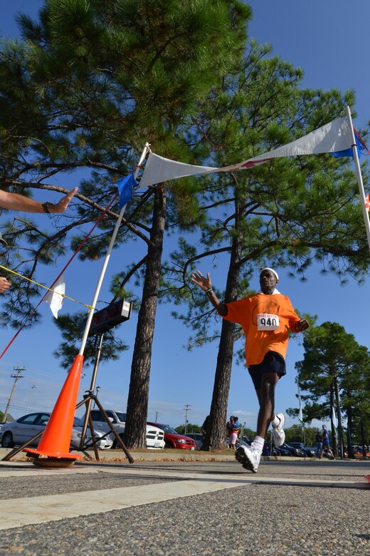 A Runner dashes to the finish line to high-five Peninsula Track club members during the Mulberry Island Half Marathon at Joint Base Langley-Eustis, Va., Sept. 17, 2016. This is the 35th year the Peninsula Track Club has put on the event with Fort Eustis.  (U.S. Air Force photo by Staff Sgt. Natasha Stannard/Released)