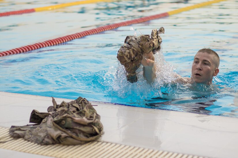 A U.S. Soldier undresses and throws his duty-uniform outside the pool while he competes during the swim test for the German Armed Forces Proficiency Badge competition Aug. 1, 2016 at Camp Arifjan, Kuwait. Sixty-five service members from U.S Army Central’s area of operations earned their GAFPB by participating in a four-day competition that tested soldier speed, agility, strength and endurance. (U.S. Army photo by Sgt. Angela Lorden)