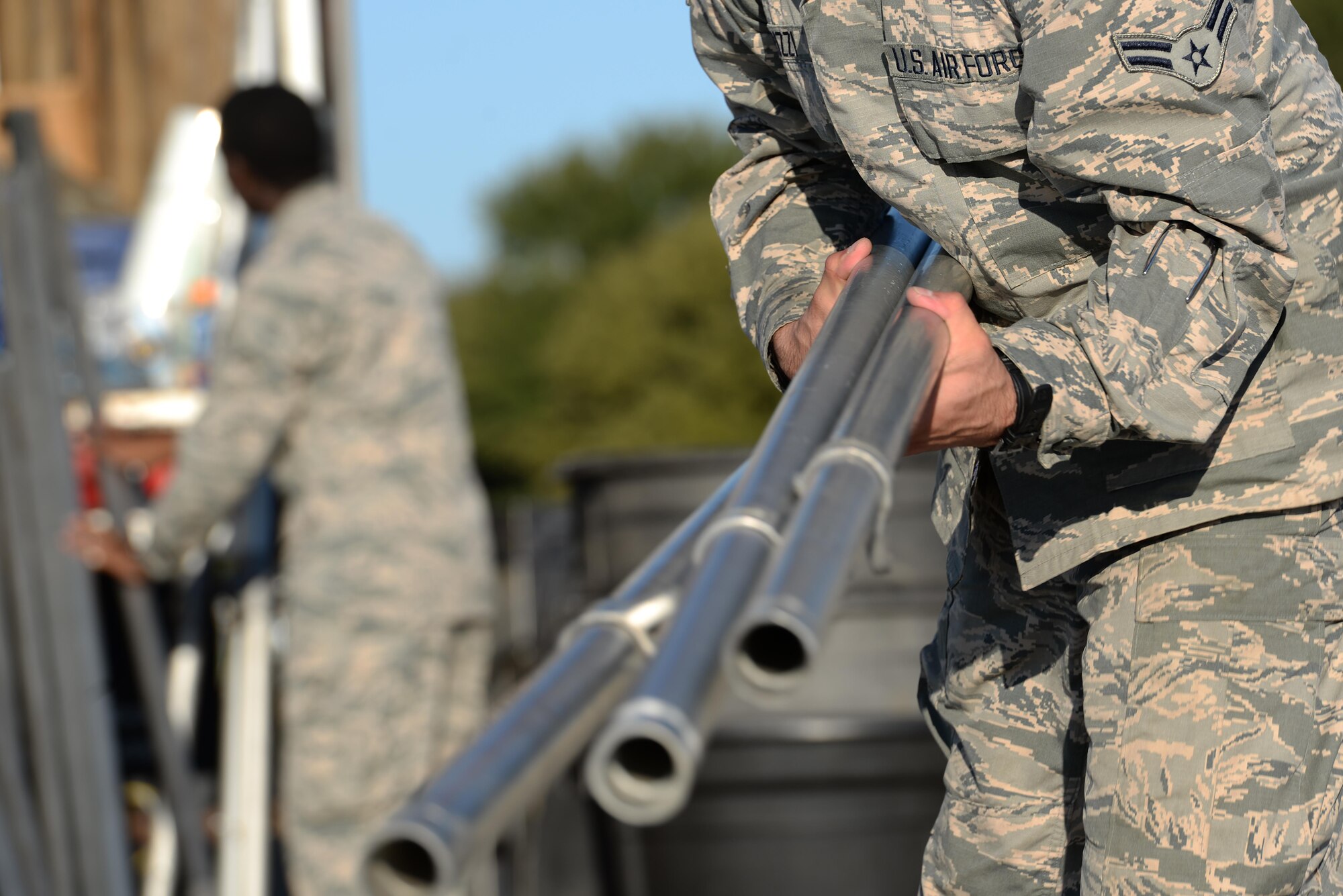 A U.S. Air Force Airman helps gathers tent poles after a storm blew down nearly every tent for the Sheppard Air Force Base, Texas, Open House and Air Show, Sept. 18, 2016. More than 2,000 Airmen in Training gathered to help reset the base for the 75th Anniversary Air Show Celebration. (U.S. Air Force photo by Senior Airman Kyle E. Gese)