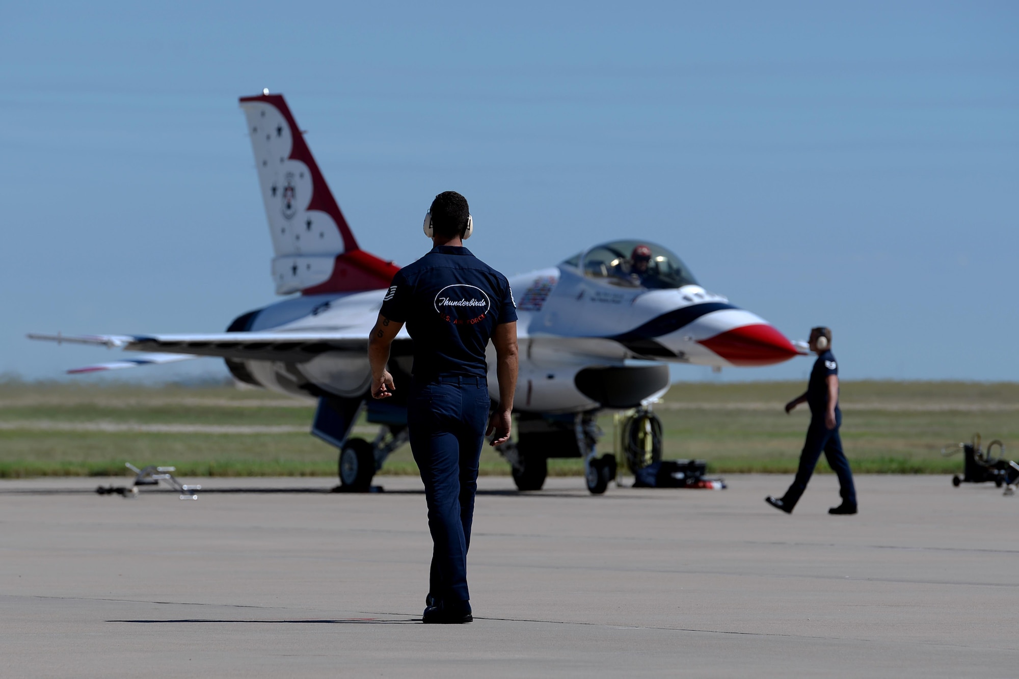 A U.S. Air Force Thunderbird crew chief walks toward the performing aircraft during the Sheppard Air Force Base, Texas, practice air show, Sept. 16, 2016. The Air Force Thunderbirds demonstrate the capabilities of the U.S. Air Force and the decisive combat power Airmen bring to threats against the United States. (U.S. Air Force photo by Senior Airman Kyle E. Gese)