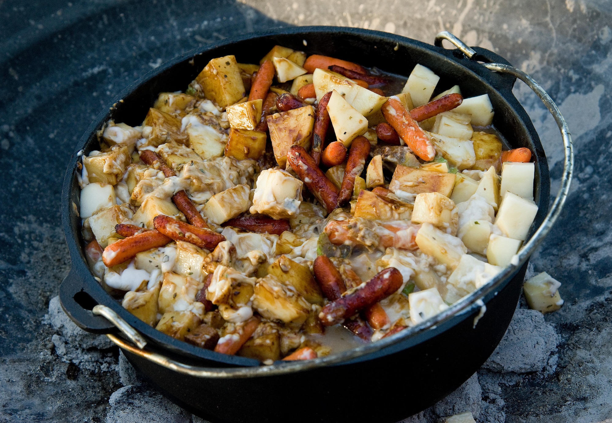 Beef stew slowly cooks in a Dutch oven Sept. 13, 2016, at the Eagle’s Nest picnic area on Dover Air Force Base, Del. Using hot charcoal in a fire pit, Senior Airman Zachary Cacicia, 436th Airlift Wing Public Affairs photojournalist, demonstrated how to make his stew recipe and cook it using a Dutch oven to Dorm to Gourm participants. (U.S. Air Force photo by Roland Balik)