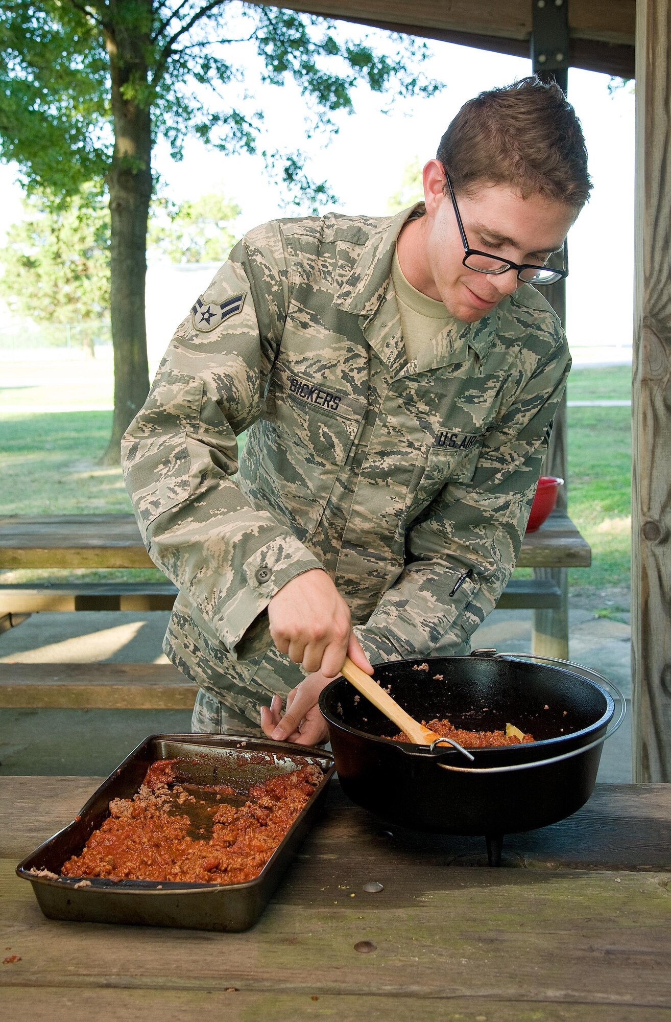 Airman 1st Class Dylan Bickers, 436th Aerospace Medicine Squadron, places cooked ground beef for lasagna in a Dutch oven Sept. 13, 2016, at the Eagle’s Nest picnic area on Dover Air Force Base, Del. Senior Airman William Johnson, 436th Airlift Wing Public Affairs photojournalist, showed Bickers and other Dorm to Gourm participants how to prepare and cook lasagna using a Dutch oven. (U.S. Air Force photo by Roland Balik)