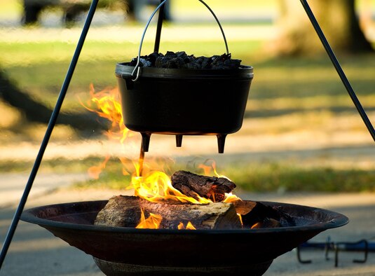 A Dutch oven containing a chicken with mushrooms, garlic butter and chipotle peppers in chicken stock hangs over an open fire Sept. 13, 2016, at the Eagle’s Nest picnic area on Dover Air Force Base, Del. Senior Airman William Johnson, 436th Airlift Wing photojournalist, taught Dorm to Gourm participants how to cook a chicken and lasagna with a Dutch oven. (U.S. Air Force photo by Roland Balik)