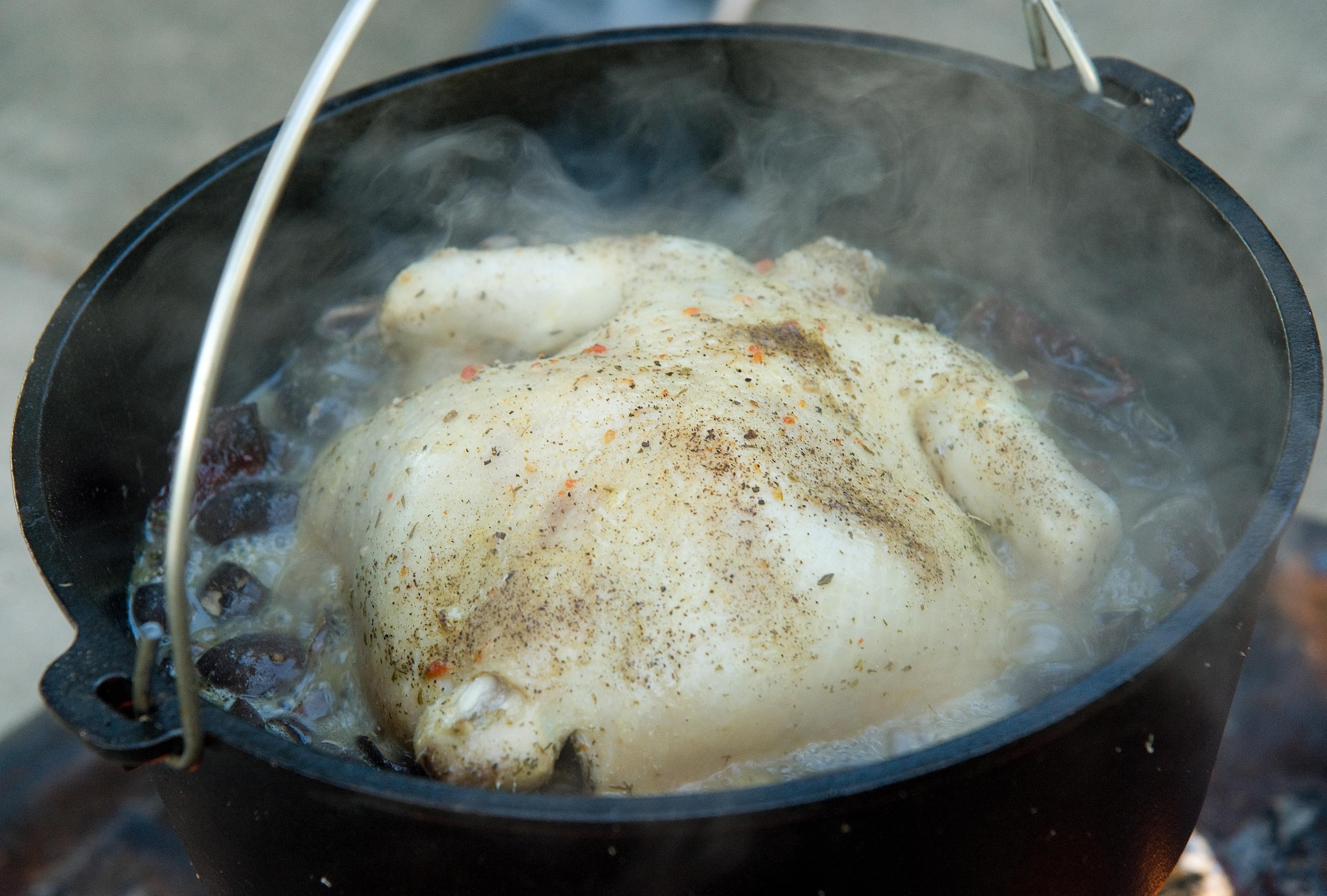 A chicken slowly boils in a Dutch oven Sept. 13, 2016, at the Eagle’s Nest picnic area on Dover Air Force Base, Del. Senior Airman William Johnson, 436th Airlift Wing photojournalist, demonstrated cooking a chicken with mushrooms, garlic butter and chipotle peppers in chicken stock to Dorm to Gourm participants. (U.S. Air Force photo by Roland Balik)
