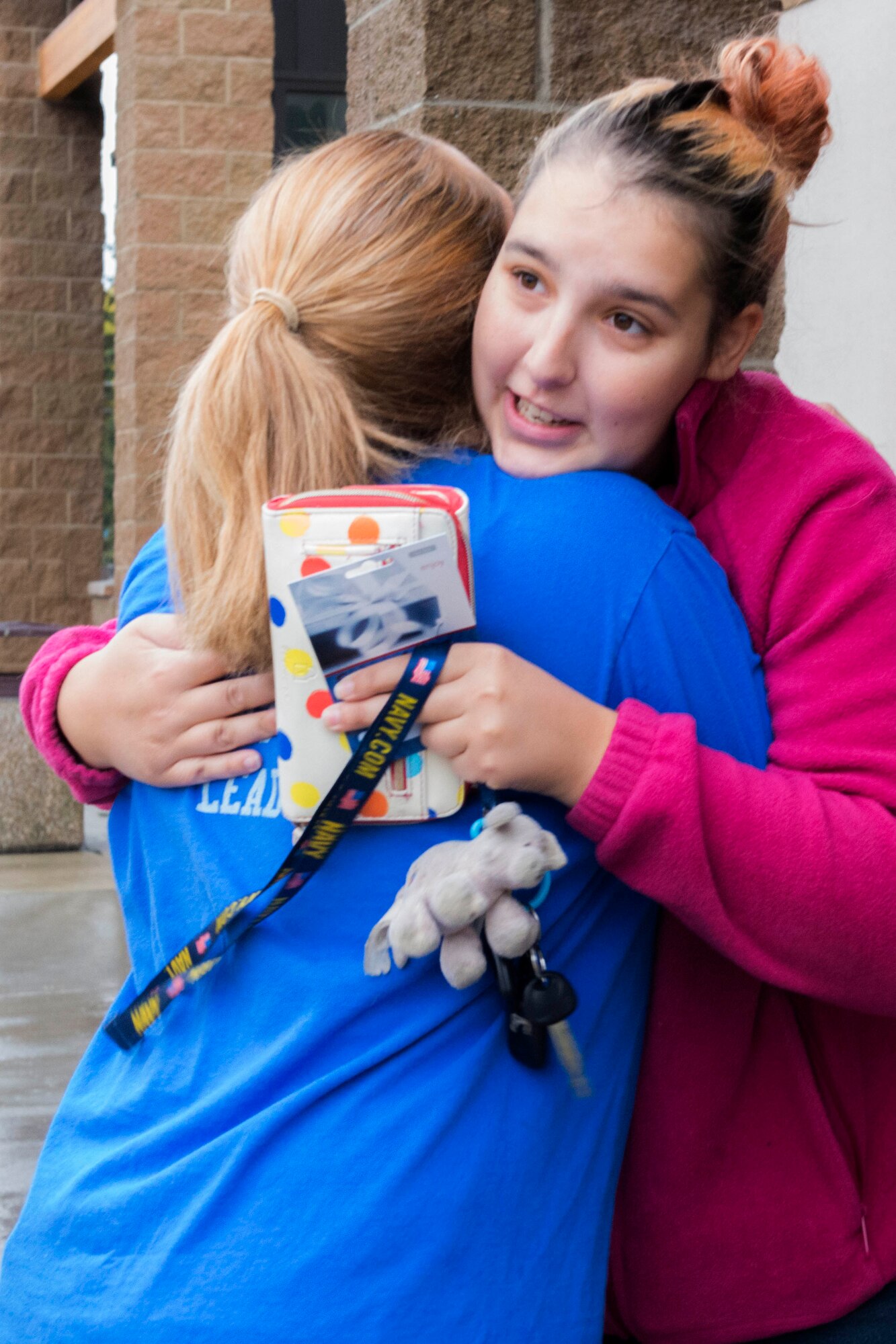 Jacquelynn Twiner, a military spouse, hugs Candace Anthony, 673d Force Support Squadron military personnel section superintendent, at the AAFES gas station at Joint Base Elmendorf-Richardson, Alaska, Sept. 16, 2016. Ten Top Three volunteers in vibrant blue shirts distributed 71 gift cards at various locations on the installation as part of the Pay It Forward Initiative. 