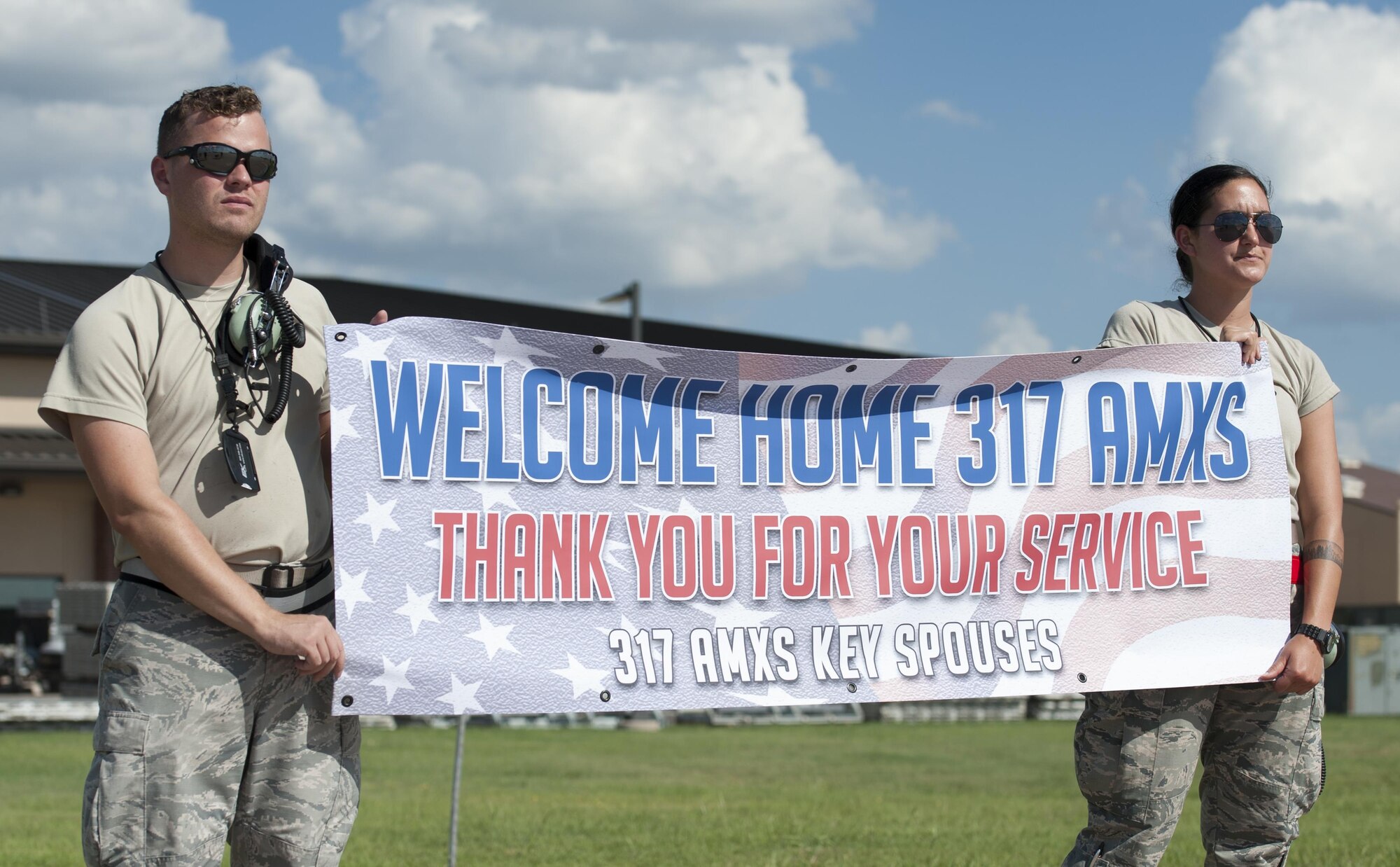 U.S. Air Force Senior Airman John Allen Kruczek and Airman 1st Class Roxanne Groschel, both 317th Aircraft Maintenance Squadron crew chiefs, hold up a sign welcoming members of the 317th AMXS returning from deployment at Dyess Air Force Base, Texas, Sept. 19, 2016. Airmen from the 317th Airlift Group and 7th Bomb Wing deployed to Djibouti, Africa in May 2016. (U.S. Air Force photo by Airman 1st Class Rebecca Van Syoc)