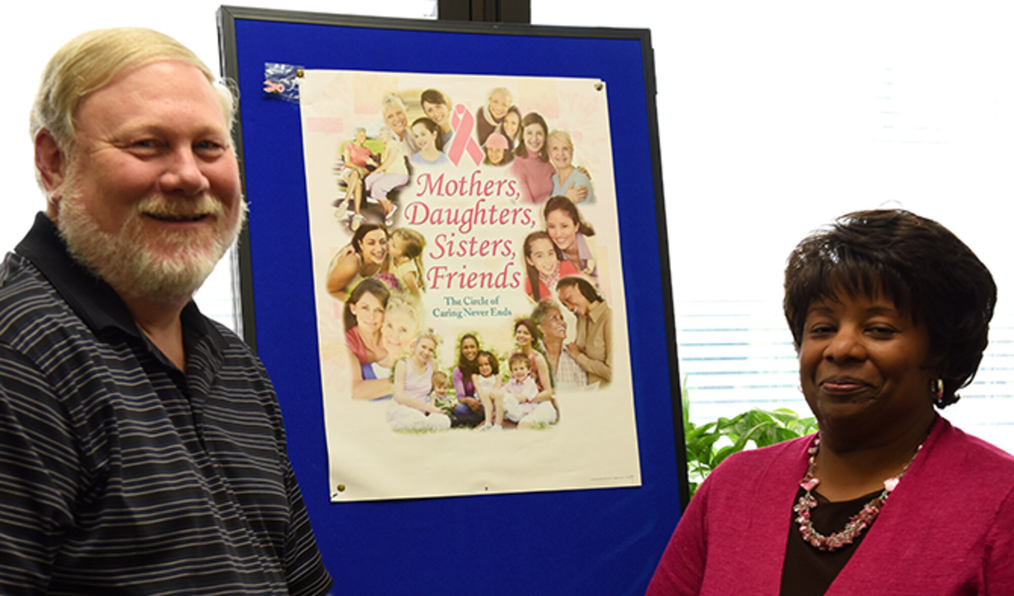 Leonard Crume, 92nd Medical Group disease management coordinator and Brenda Traylor, 92nd MDG family health administrative scheduler, pose next to a breast cancer awareness poster Sept. 15, 2016, at Fairchild Air Force Base, Washington. October is Breast Cancer Awareness Month. (U.S. Air Force photo/Airman 1st Class Ryan Lackey)