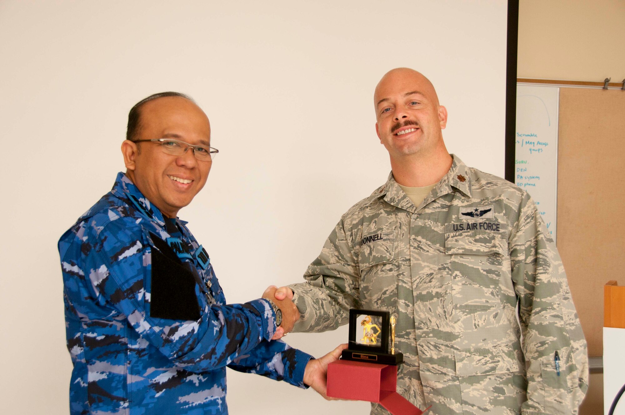 U.S. Air Force Maj. Michael O'Donnell accepts a gift of gratitude at the final day awards ceremony for the Subject Matter Expert Exchange, from the Indonesian air defense delegation's head officer Col. Palito Sitorus. This is the second time a Subject Matter Expert Exchange between the Indonesian air defense and the 169th Air Defense Squadron has been conducted and the first time the Indonesians have come to Hawaii. (U.S. Air National Guard photo by Airman 1st Class Stan Pak/released)