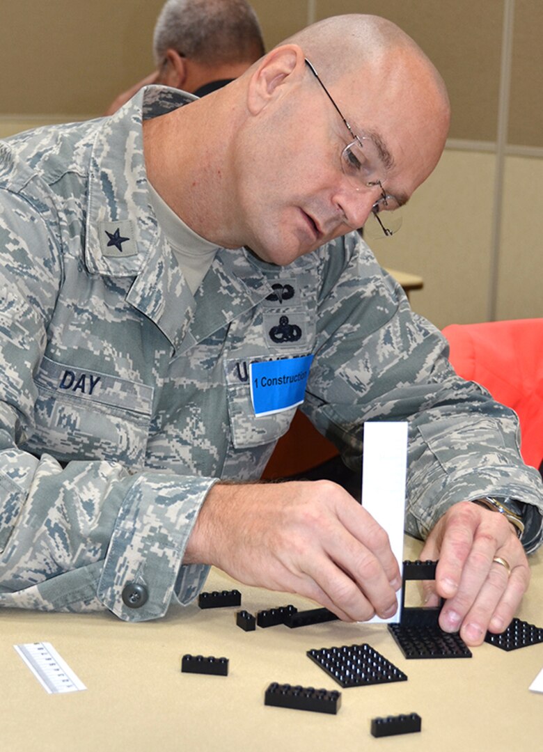 Air Force Brig. Gen. Allan Day, Defense Logistics Agency Aviation commander, works intently building a toy house from interconnecting blocks to demonstrate communication, common goals, and constraint resolution during an Aviation Process Excellence training exercise in the Lotts Conference Center Sept. 8-9 on Defense Supply Center Richmond, Virginia. 