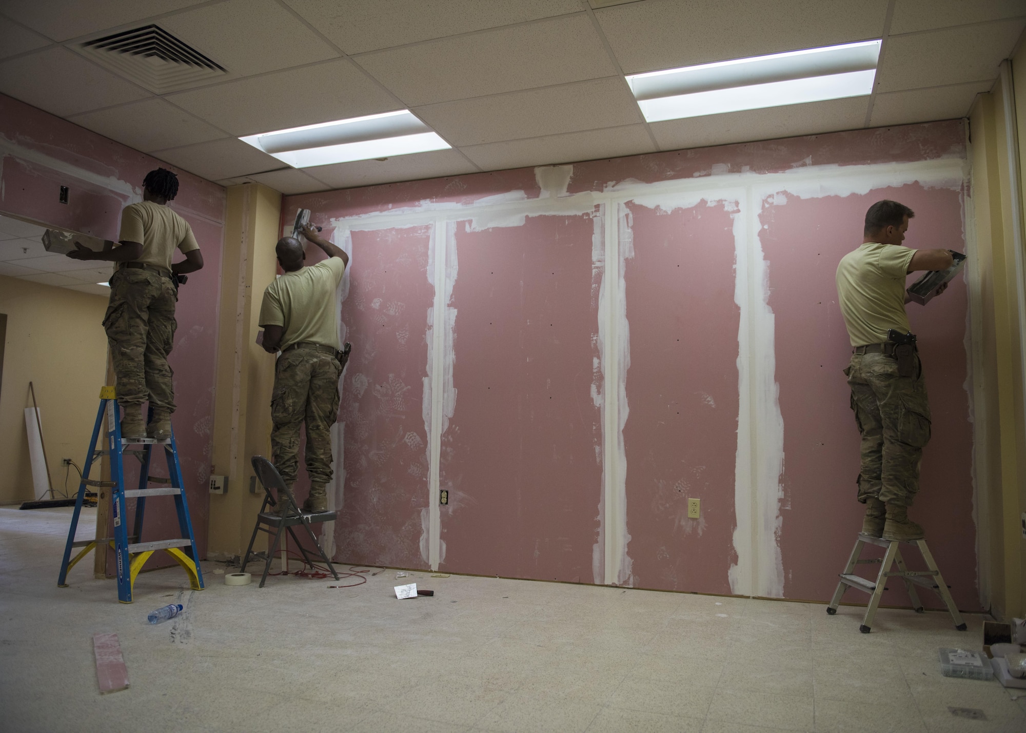 Airman 1st Class Taylor Davis, Staff Sgt. Donald Scott, and Senior Airman Eric Woolston, 455th Expeditionary Civil Engineer Squadron structural airmen, apply joint compound which helps seal joints between drywall, Bagram Airfield, Afghanistan, Sept. 20, 2016. Structural specialists have a varied skill set that is used along with specialized materials, and equipment to build numerous structures that range from locker rooms to improvised emergency disaster relief shelters. (U.S. Air Force photo by Senior Airman Justyn M. Freeman)