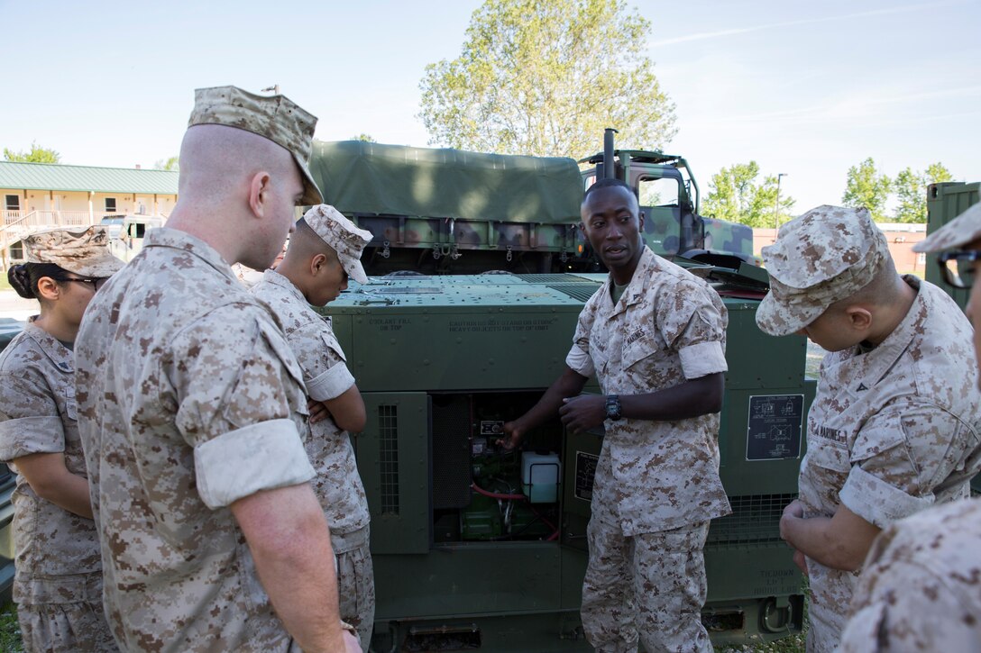 Lance Cpl. Torffic Hassan (second from the right), an engineer with 6th Communications Battalion, Force Headquarters Group, gives a lesson on  generator system functions to his fellow Marines at the Muscatatuck Urban Training Center in Butlerville, Ind., June 8, 2016. Hassan immigrated to the United States in 2009 to pursue education.  (U.S. Marine Corps photo by Cpl. Melissa Martens/ Released)