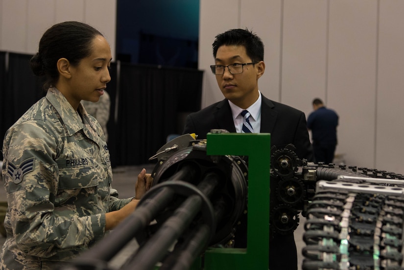U.S. Air Force Senior Airman Chaleah Phillips, 1st Maintenance Squadron aircraft armament systems journeyman, explains the Gatling gun display to Sam Kim, defense contractor, at the 100-year Gala celebration at the Hampton Roads Convention Center in Hampton, Va., Sept. 17, 2016. Langley Air Force Base is the oldest continuously operating active air base in the U.S. (U.S. Air Force photo by Airman 1st Class Derek Seifert)
