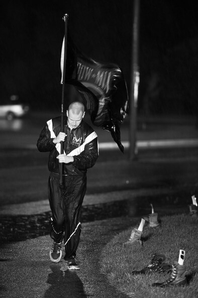 An Airman carries the Prisoners of War/Missing in Action flag through the rain at Minot Air Force Base, N.D., Sept. 15, 2016. Airmen from across both wings ran the POW/MIA flag around the outdoor track for 24 hours in honor of those who are lost but not forgotten. (Airman 1st Class J.T. Armstrong)