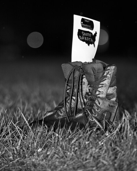 Combat boots line the outdoor track in the rain at Minot Air Force Base, N.D., Sept. 15, 2016. The boots symbolized prisoners of war and missing in action service members during a POW/MIA memorial event. (Airman 1st Class J.T. Armstrong)