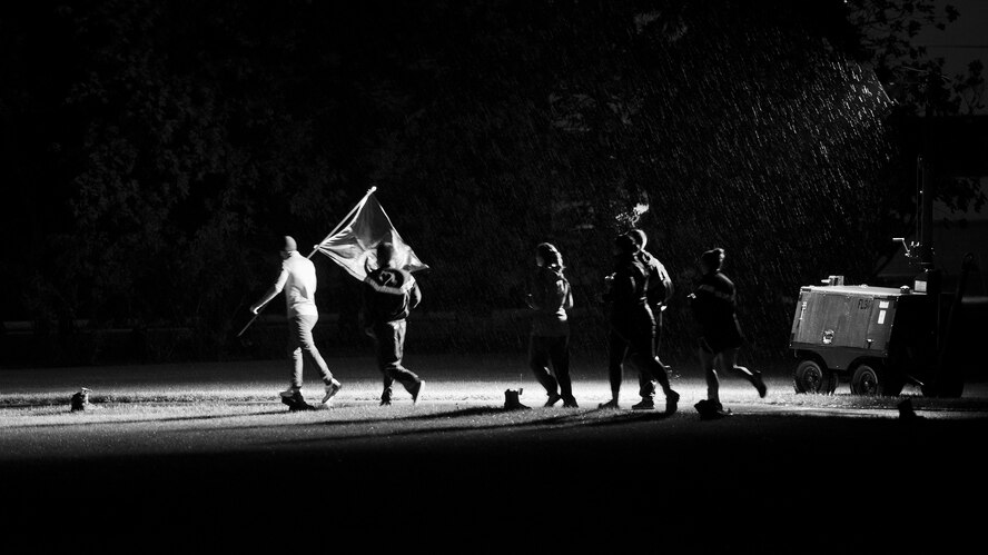 A group of Team Minot Airmen run through the rain during a memorial event at Minot Air Force Base, N.D., Sept. 15, 2016. Throughout the night Airmen traded off carrying the Prisoners of War/Missing in Action flag around the outdoor track. (Airman 1st Class J.T. Armstrong)