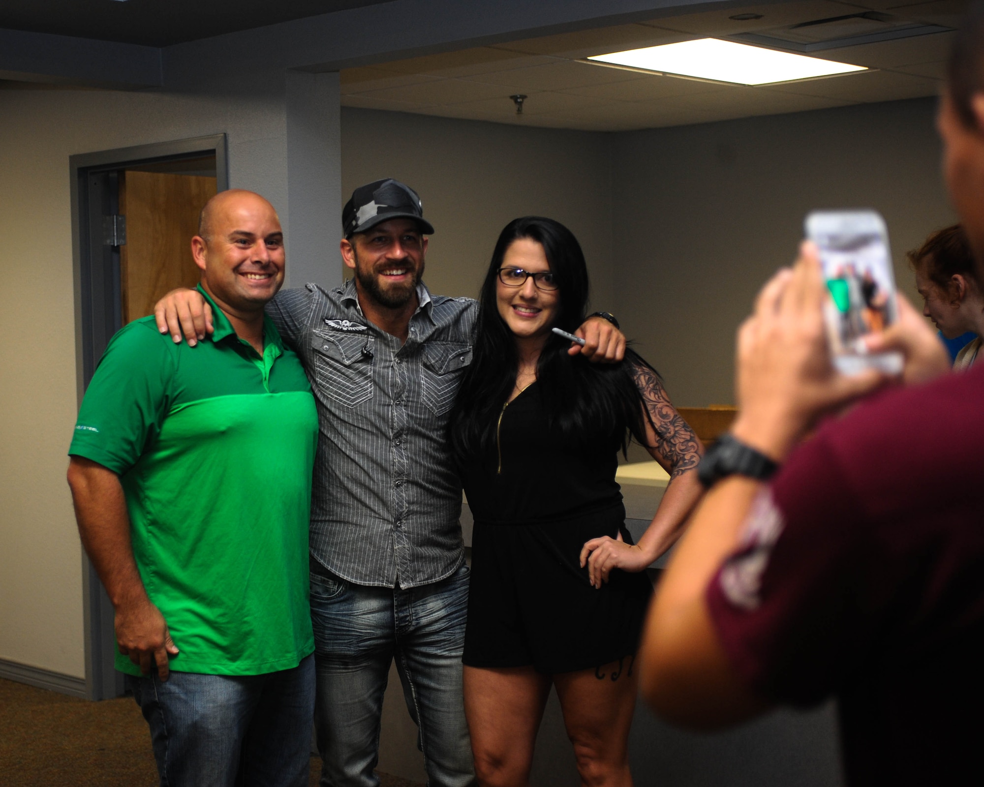 Kyle Jennings, a country music artist, poses for pictures with Airmen and their families after his concert at Barksdale Air Force Base, La., Sept. 16, 2016. Jennings took time after the concert to autograph memorabilia for the fans. (U.S. Air Force photo/Airman 1st Class Stuart Bright)