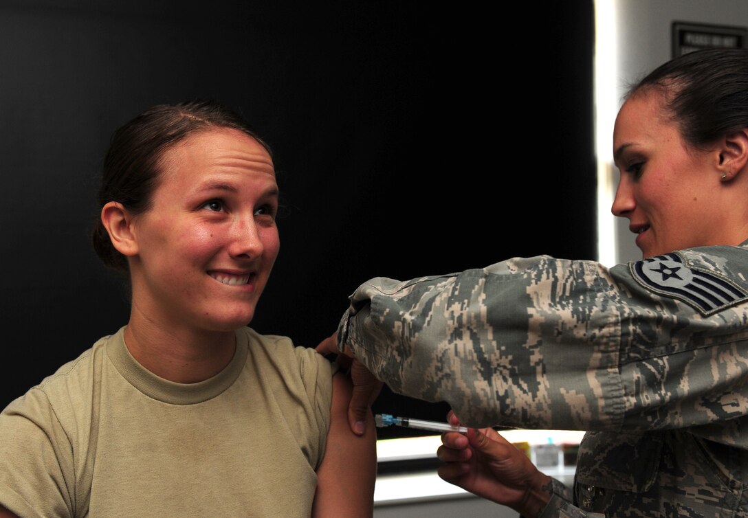 U.S. Air Force Staff Sgt. Hilary Tenebruso, right, vaccinates Airman 1st Class Amanda Murdock, both 7th Medical Operations Squadron medical technicians, at Dyess Air Force Base, Texas, Aug. 31, 2016. Each month the immunizations flight provides an average of 800 to 900 doses. (U.S. Air Force photo by Staff Sgt. Peter Thompson)