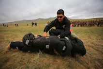 U.S. Marine Cpl. Ezequiel Silva, a military police Marine with 3rd Law Enforcement Battalion, III Marine Expeditionary Force, demonstrates a mechanical advantage control holds technique during Non-Lethal Weapons Executive Seminar (NOLES) 2016 at the Five Hills Training Area, Mongolia, Sept. 17, 2016. Mongolian soldiers and National Police were exposed to oleoresin capsicum spray and had to complete a five-level circuit course. Non-lethal weapons are designed to incapacitate equipment and personnel while minimizing fatalities and permanent injury to personnel, and undesired collateral damage to property.  (U.S. Marine Corps photo by Cpl. Jonathan E. LopezCruet)