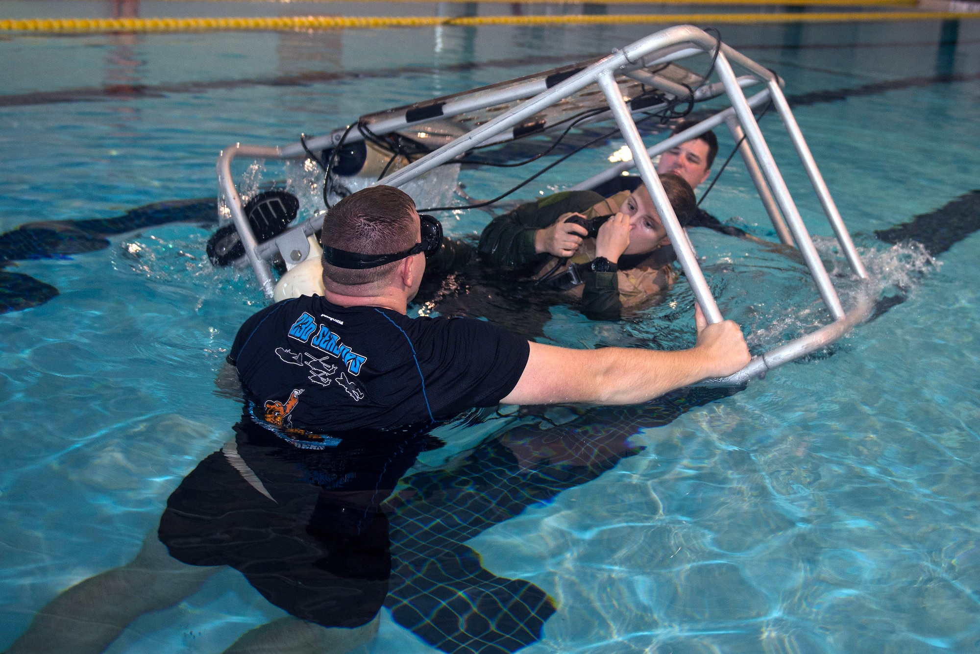 U.S. Air Force Tech. Sgt. Travis Siegwart, 347th Operations Support Squadron NCO in charge of survival, evasion, resistance and escape training, front, and Staff Sgt. Andrew McIntosh, 347th Rescue Group NCO in charge of SERE training, back, tips Senior Airman Shelbi Bear, 41st Rescue Squadron special missions aviator, in an underwater egress trainer during water survival training, Sept. 15, 2016, at Moody Air Force Base, Ga. Since HH-60G Pave Hawks don’t possess parachutes, aircrew members have to get out and breathe on compressed air through scuba bottles in the event of ejecting from the airframe over water. (U.S. Air Force photo by Airman 1st Class Greg Nash)