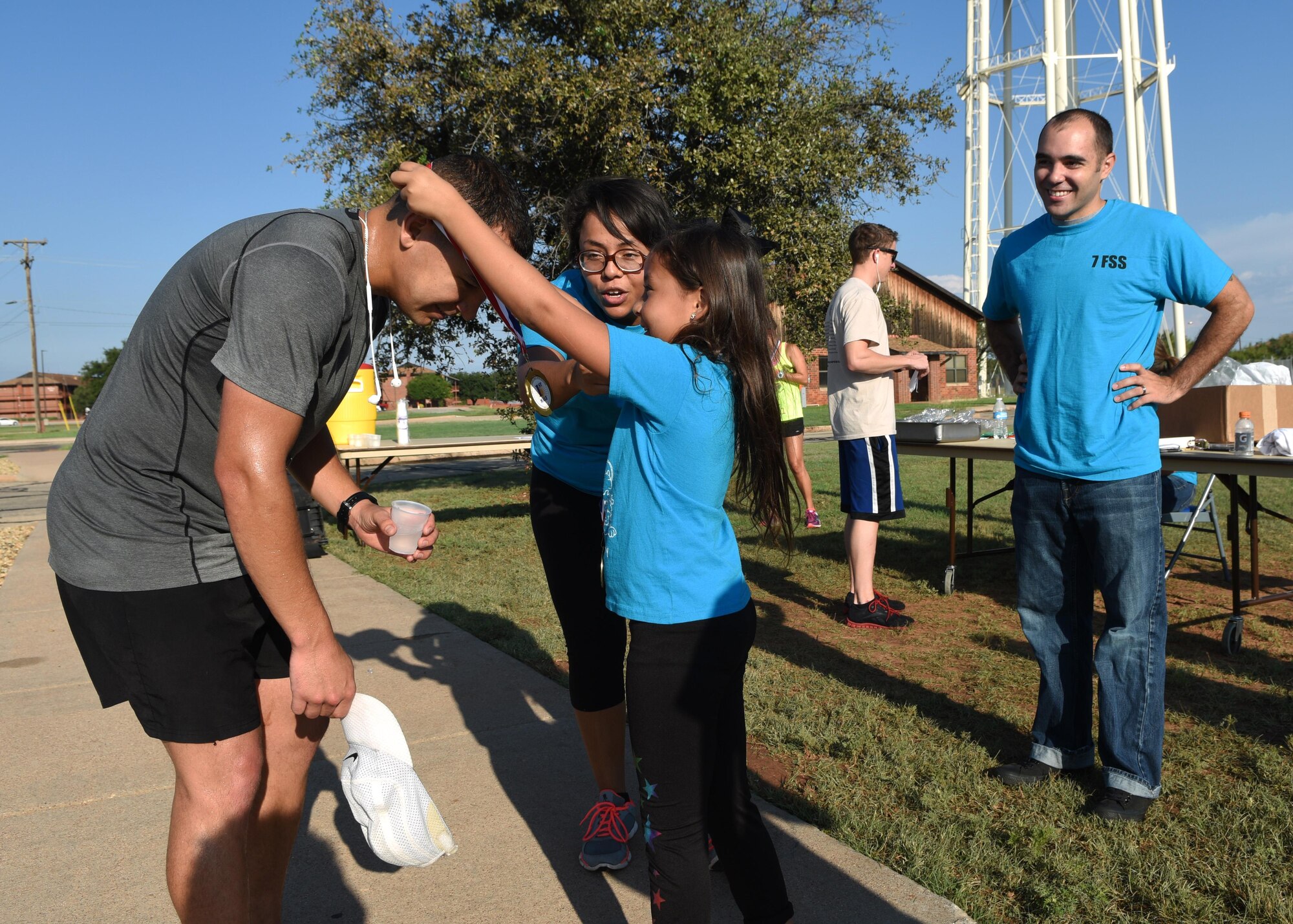 U.S. Marine Corps Staff Sgt. Jason Garcia, Combat Logistics Battalion 453 Detachment 1 small arms repair technician, receives a medal from Akira, daughter of Staff Sgt. Marcela Huerta, 7th Force Support Squadron fitness assessment cell manager, during the Dyess Mini Marathon, at Dyess Air Force Base, Texas, Sept. 17, 2016. Garcia was the first to finish the half marathon with a time of 1:29:08. (U.S. Air Force photo by Senior Airman Kedesha Pennant)