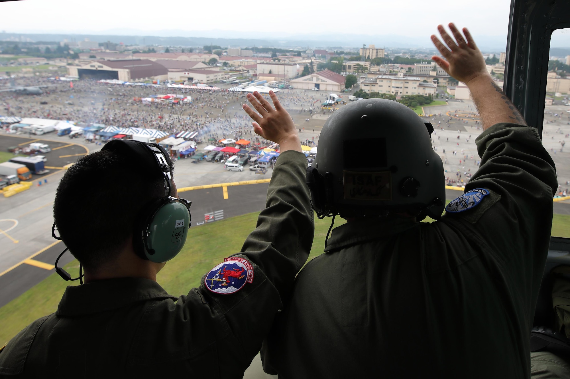 1st Lt. Kaleb Young, 459th Airlift Squadron UH-1N Iroquois pilot, and Tech. Sgt. Christopher Rector, 459 AS flight engineer, wave to festivalgoers over Yokota Air Base, Japan, Sept. 17, 2016, during the 2016 Japanese-American Friendship Festival. The 459 AS demonstrated their airlift capabilities to festivalgoers. Yokota welcomed over 135,000 visitors to the festival. (U.S. Air Force photo by Yasuo Osakabe/Released) 