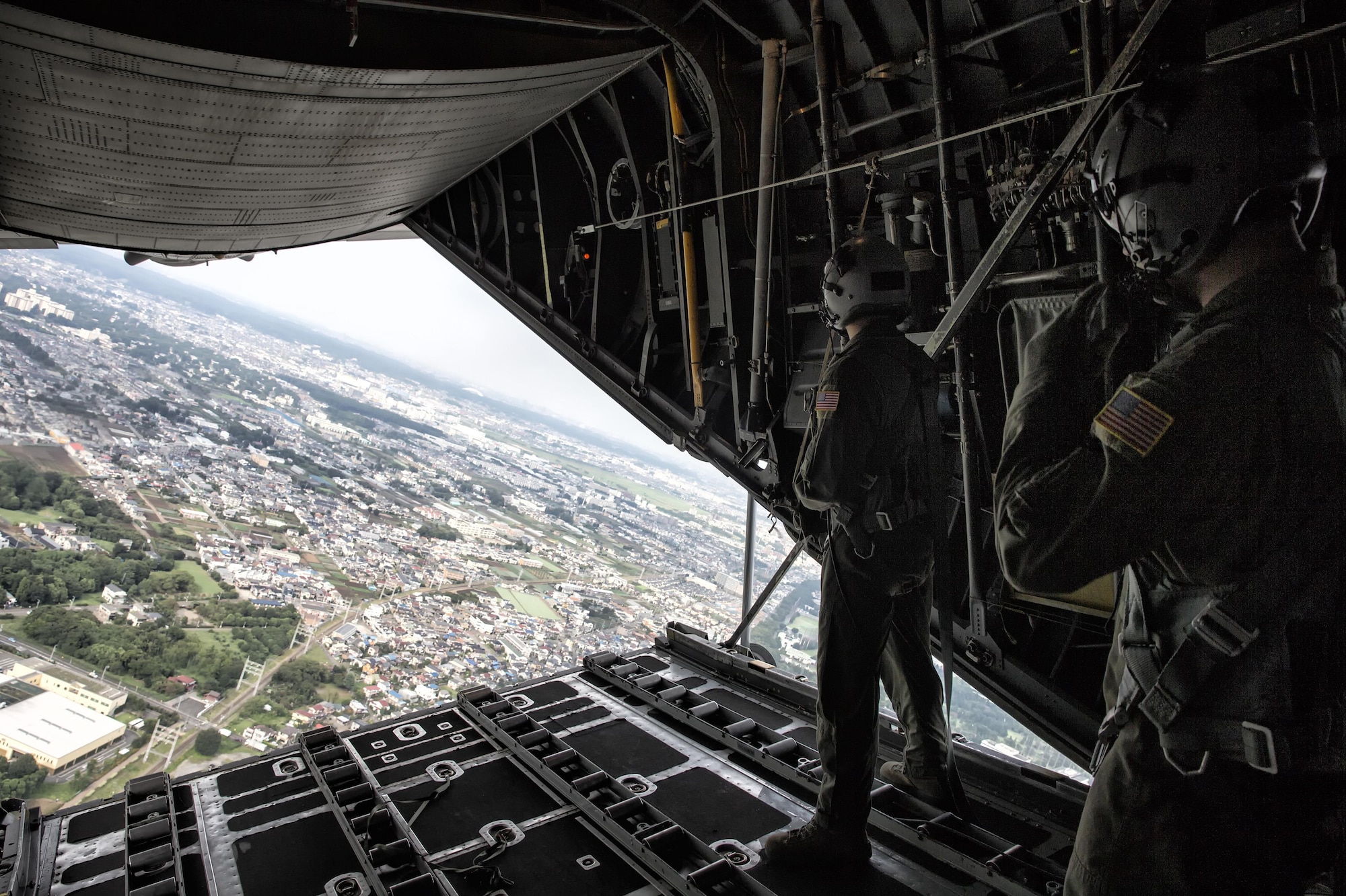 (Left to right) Senior Airman Andrew Fox and Tech. Sgt. Kyle Favorite, both with the 36th Airlift Squadron C-130H loadmasters, perform visual conformation over Yokota Air Base, Japan, Sept. 17, 2016, during the American-Japanese Friendship Festival. The 36 AS demonstrated their airdrop capabilities to festivalgoers. Yokota welcomed over 135,000 visitors for the festival. (U.S. Air Force photo by Yasuo Osakabe/Released)   
