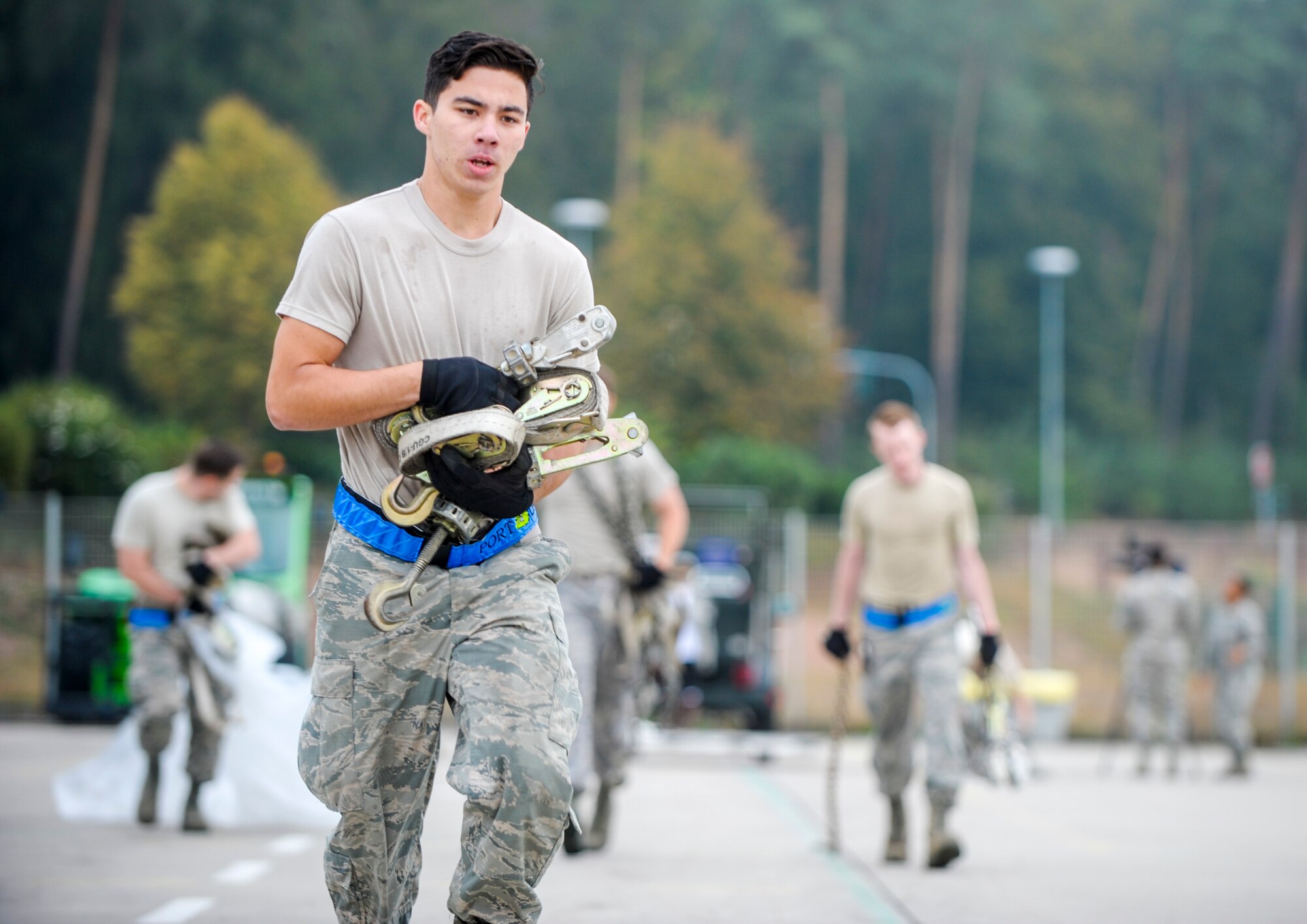 Airman 1st Class Tommy Huynh, 721st Aerial Port Squadron cargo processing specialist, carries ratchet straps during the physical challenge obstacle course of the 2016 European Port Dawg Rodeo Sept. 17, 2016, at Ramstein Air Base, Germany.  For the course, Airmen had to unload a pallet, move the items and the pallet approximately 100 yards away, rebuild the pallet and run a relay around an apron. (U.S. Air Force photo/Staff Sgt. Timothy Moore)