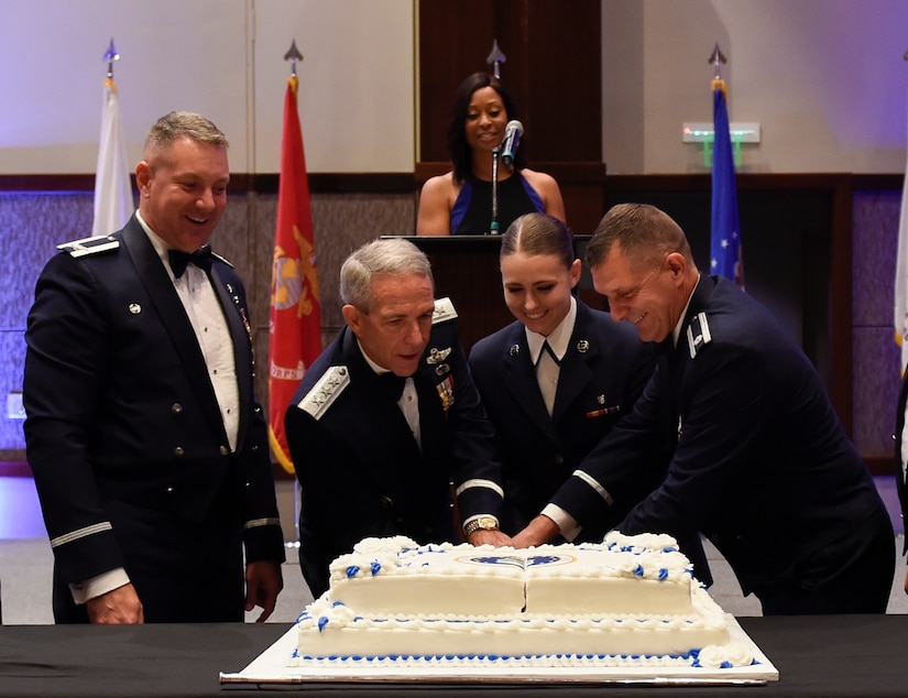 U.S. Air Force retired Lt. Gen. Brooks L. Bash (second from the left), Airman 1st Class Cassandra Macdonald, 628th Medical Group records technician (second from the right) and Lt. Col. Walter Bean, 628th Airbase Wing chaplain (right) cut the cake with a saber during the 2016 Air Force Ball Sept. 17, 2016 at the Charleston Convention Center here. It is tradition for the youngest and oldest Airmen to cut the cake together signifying respect and honor afforded to experience and seniority while symbolizing the newer generation of Airmen filling the ranks.