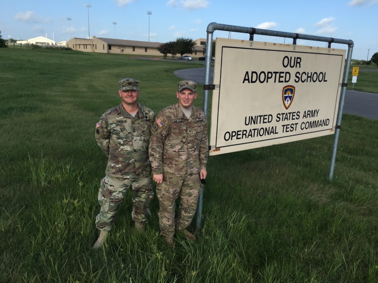 Army Master Sgt. Earnest L. Vance, U.S. Army Operational Test Command's Test Technology Directorate noncommissioned officer in charge, left, and Army Sgt. Jacob D. Wilson, command group NCOIC, stand before OTC's Adopt-A-School sign at Florence Middle School, Florence, Texas, Sept. 9, 2016. Army photo by Michael Novogradac