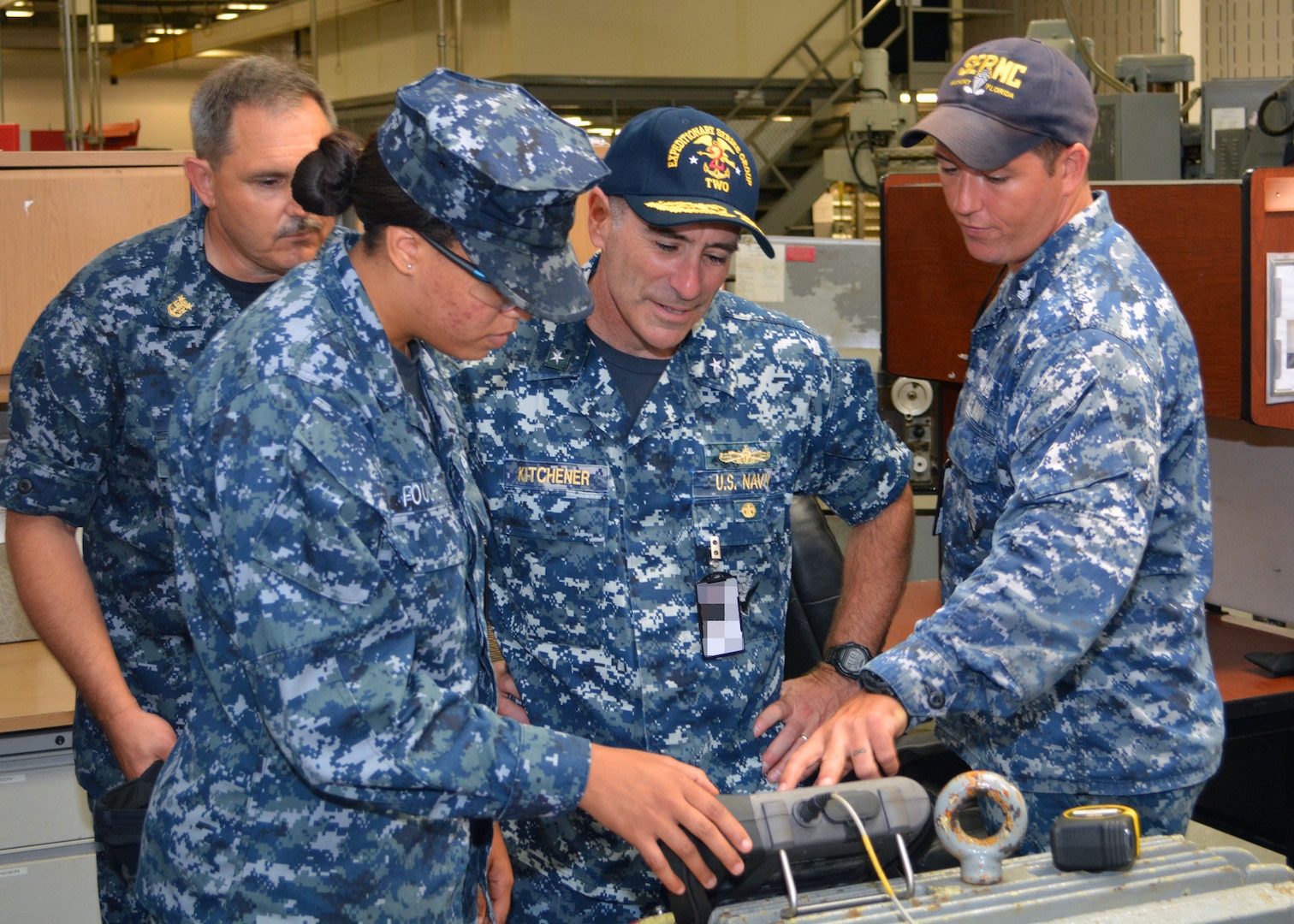 Machinist's Mate 2nd Class Zachary Kennedy (far right) and Machinist's Mate Fireman Brianna Fouche explain to Expeditionary Strike Group 2 Commander Master Chief Kevin Goodrich (L), and Rear Adm. Roy Kitchener how they use precision laser equipment to align shafts and motors on a firemain pump at Southeast Regional Maintenance Center (SERMC). Kitchener and Goodrich visited SERMC Tuesday. In an average calendar year, the Pump Shop at SERMC repairs more than 60 pumps, and all are calibrated using the precision laser alignment tool.