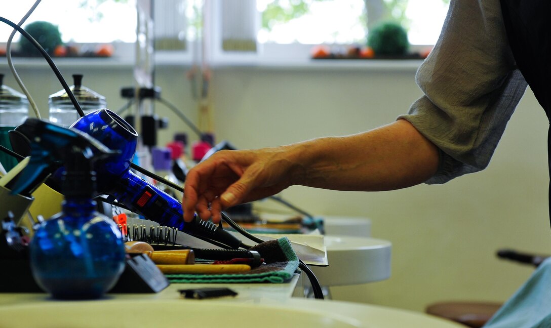 Claudia Gomez, barber, reaches for her array of barber tools as she cuts a customer’s hair Sept. 20, 2016, at Ramstein Air Base, Germany. After working on Ramstein for 20 years and gaining confidence in her abilities, she became the owner of the barber shop in 2001. (U.S. Air Force photo/Airman 1st Class Lane T. Plummer)