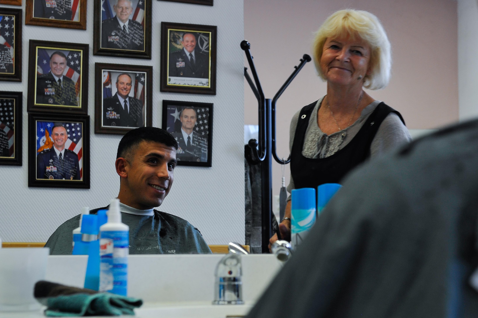 Claudia Gomez, barber, shares a conversation with her customer, Airman 1st Class Hector Montoya, 721st Aerial Port Squadron passenger service agent, Sept. 20, 2016, at Ramstein Air Base, Germany. Gomez believes in recreating a “close to home” atmosphere with her shop, and enjoys getting to know the people that come in and helping them feel comfortable. (U.S. Air Force photo/Airman 1st Class Lane T. Plummer)