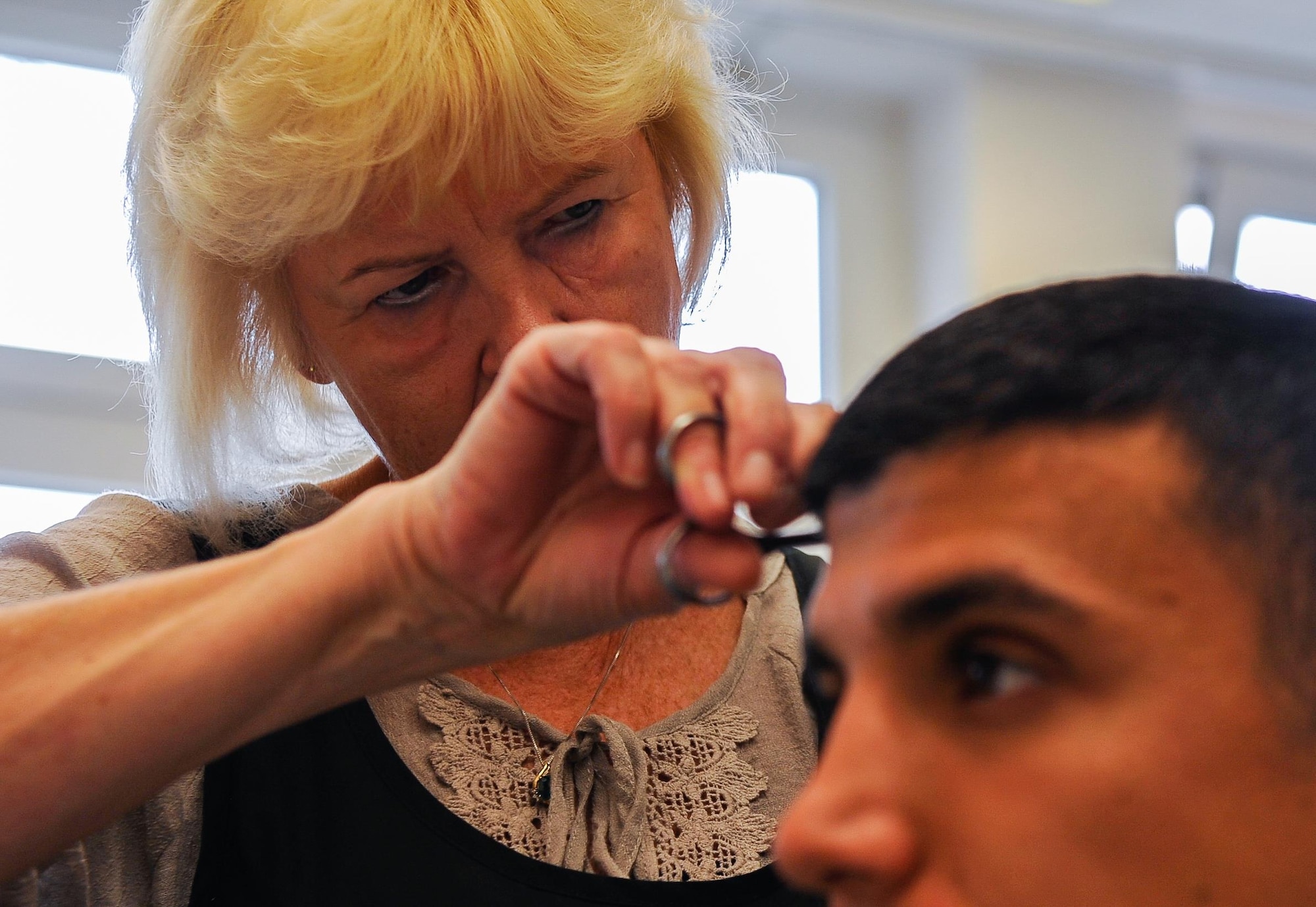 Claudia Gomez, barber, cuts Airman 1st Class Hector Montoya’s hair, 721st Aerial Port Squadron passenger service agent, Sept. 20, 2016, at Ramstein Air Base, Germany. Gomez has cut hair for thousands of Airmen and families over the 35 years she’s worked on base. (U.S. Air Force photo/Airman 1st Class Lane T. Plummer)