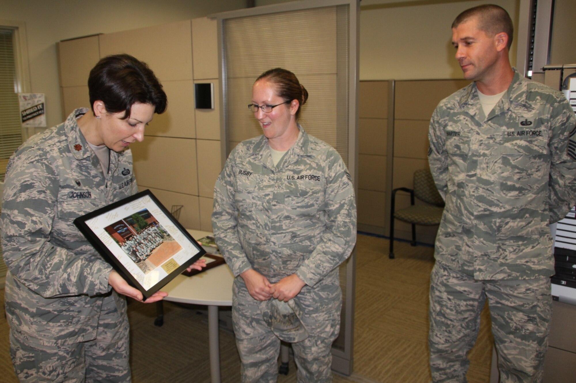 Maj. Melissa Johnson presents a special team photo to her outgoing 932nd Services Flight member, Senior Airman Jessica Busby, while Senior Master Sgt. Joseph Harter looks on as she moves to another unit.  (U.S. Air Force photo by Maj. Stan Paregien)