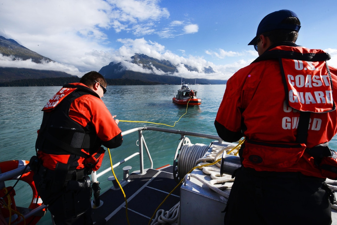 Coast Guard Petty Officer 3rd Class John Gerbrands, left, guides a rescue heaving line aboard the 45-foot response boat to a 25-foot response boat during crewman qualification training in Valdez Harbor on Prince William Sound, Alaska, Sept. 13, 2016. Gerbands is assigned to Coast Guard Station Valdez. Coast Guard photo by Petty Officer 1st Class Bill Colclough